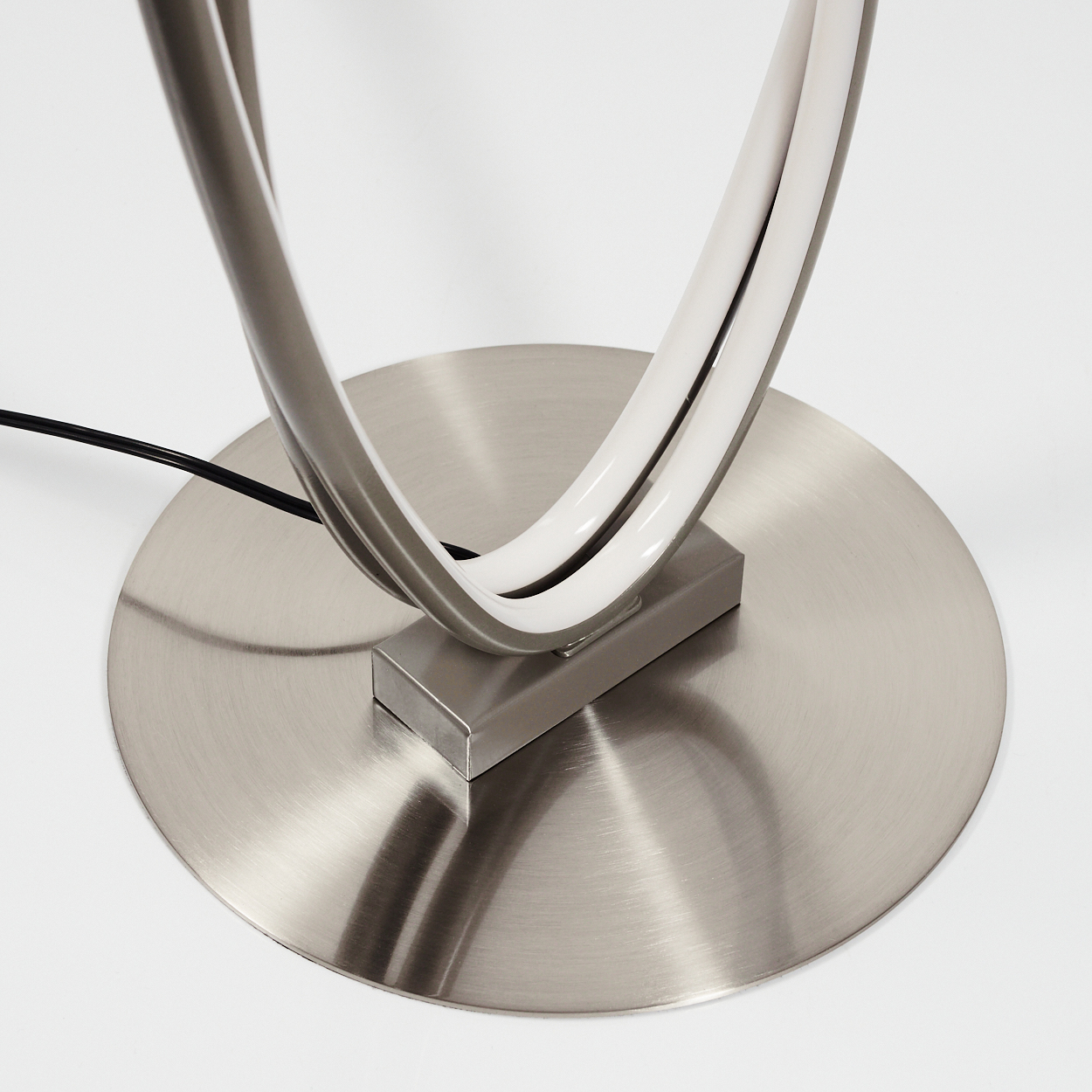 Nahaufnahme des Sockels einer modernen Stehlampe. Der Sockel ist eine kreisförmige Metallscheibe mit Silberfinish.