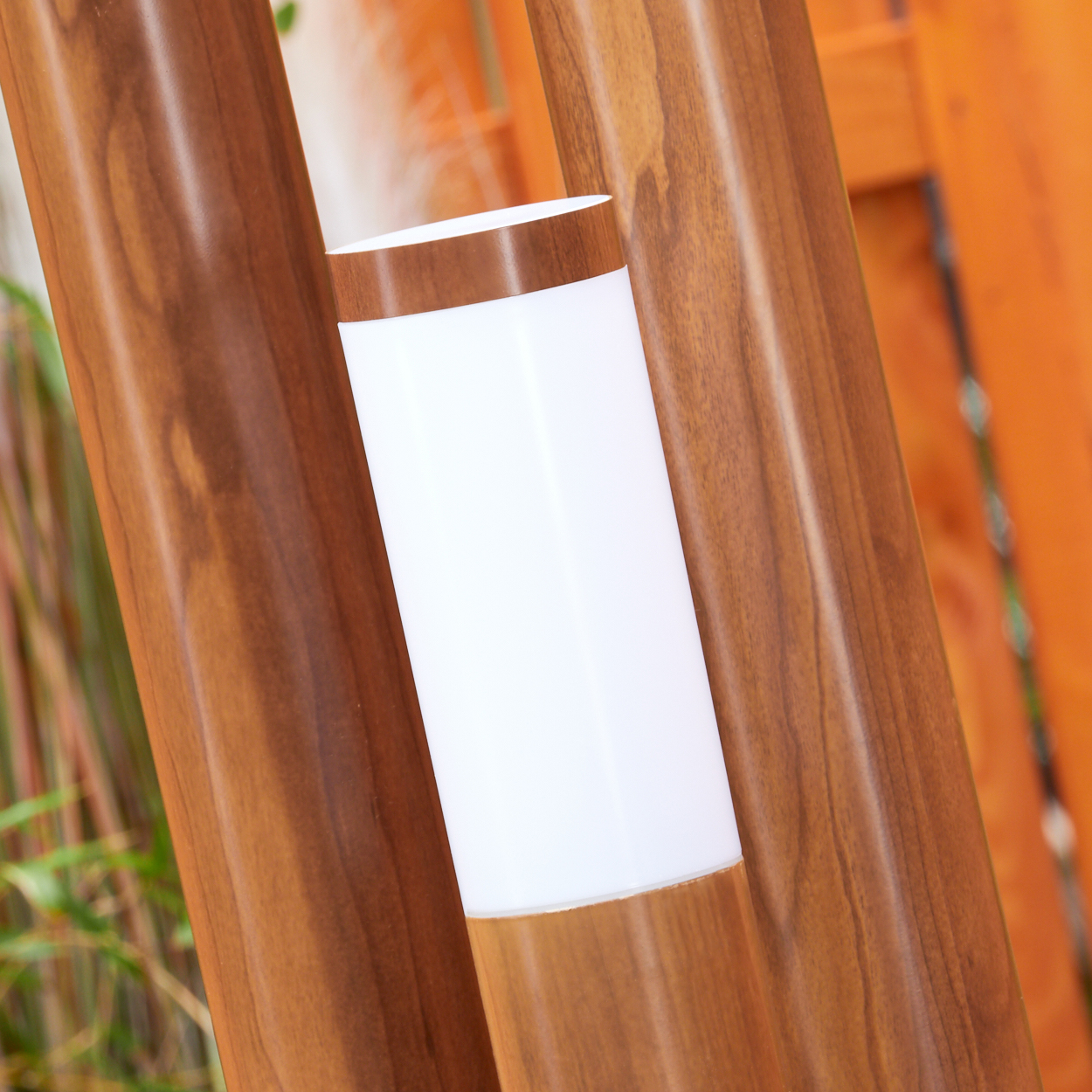 Nahaufnahme einer Holzlampe mit drei Holzpfählen und weißen Lichtern. Der Hintergrund ist unscharf.