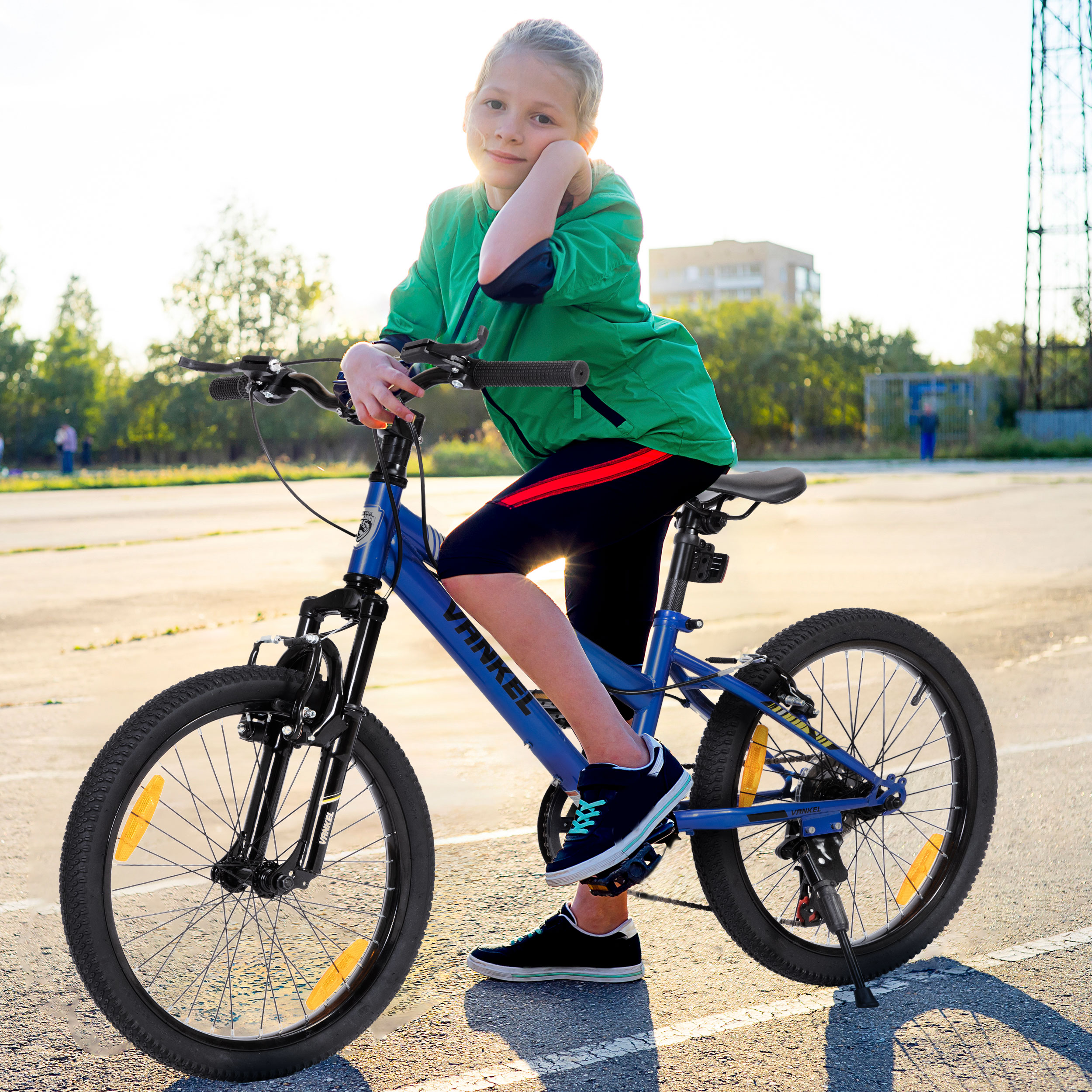 Ein Mädchen sitzt auf einem blauen Fahrrad und stützt sich auf den Arm. Das Fahrrad hat schwarze Reifen, und das Mädchen trägt Grün, Schwarz und Rot.