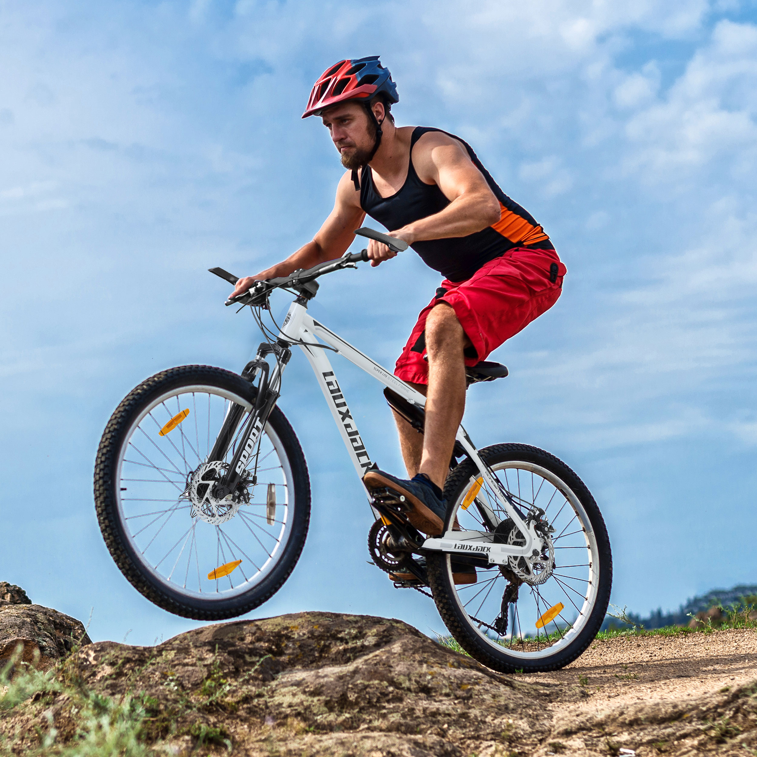 Mann in roten Shorts fährt mit einem weißen Fahrrad und springt auf einem Feldweg.