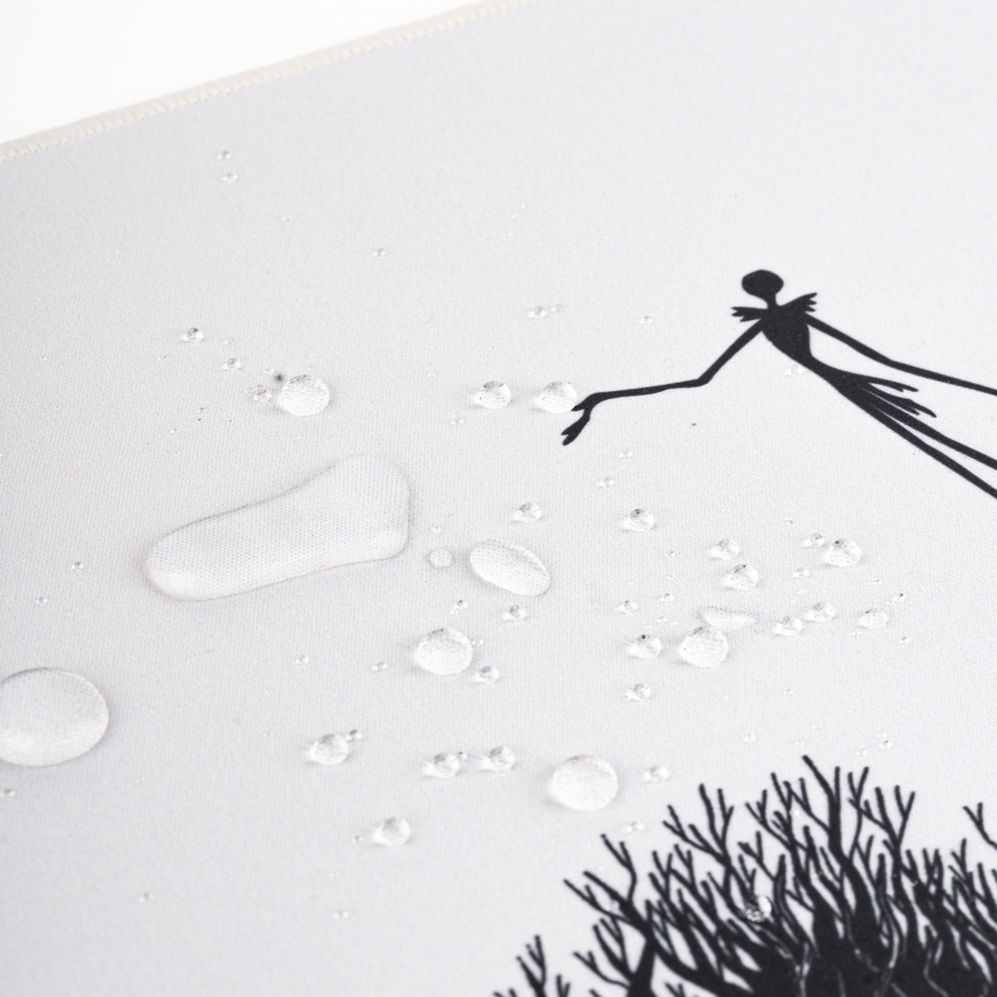 Ein weißes Mauspad mit einer schwarzen Silhouette von Jack Skellington. Wassertropfen befinden sich auf der Oberfläche.