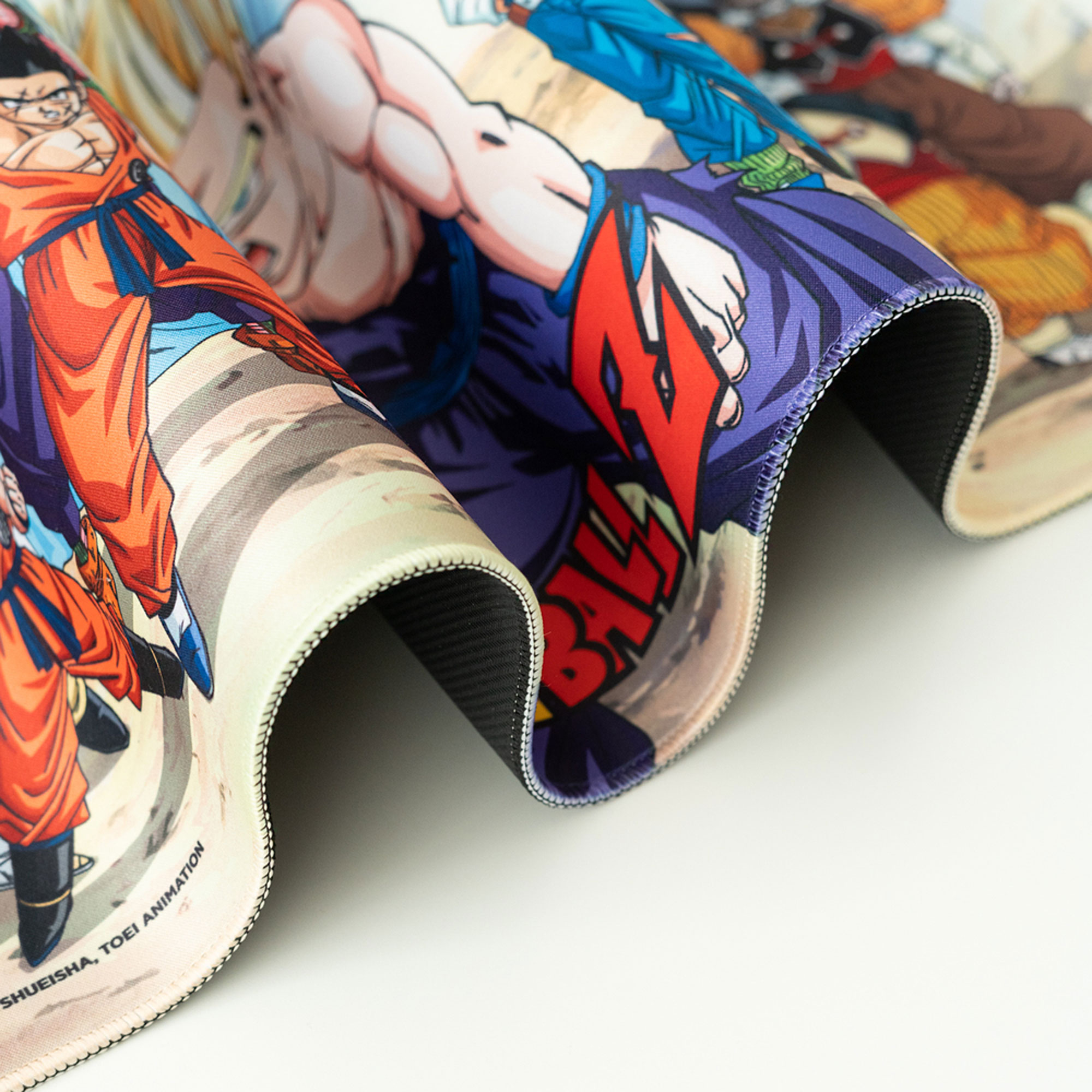 Aufgerolltes Dragon Ball Z-Mauspad mit farbenfrohem Aufdruck von Anime-Charakteren. Weißer Hintergrund.