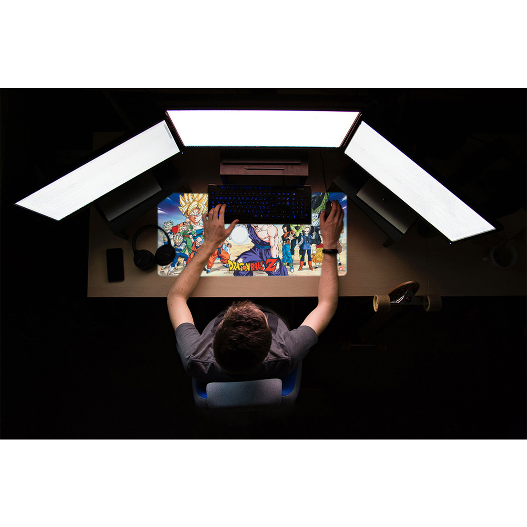 Draufsicht einer Person, die ein Dragon Ball Z Mauspad benutzt. Auf dem Schreibtisch befinden sich drei Monitore und eine Tastatur.