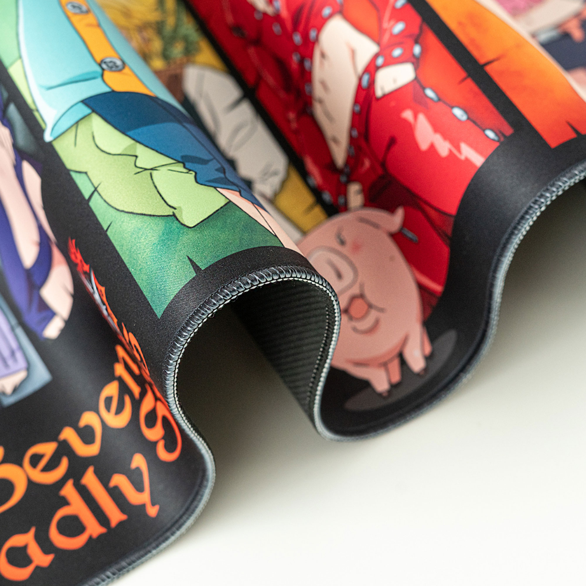Nahaufnahme des Mousepads mit Anime-Charakteren und Text, zeigt gerollten Rand und Nähte.