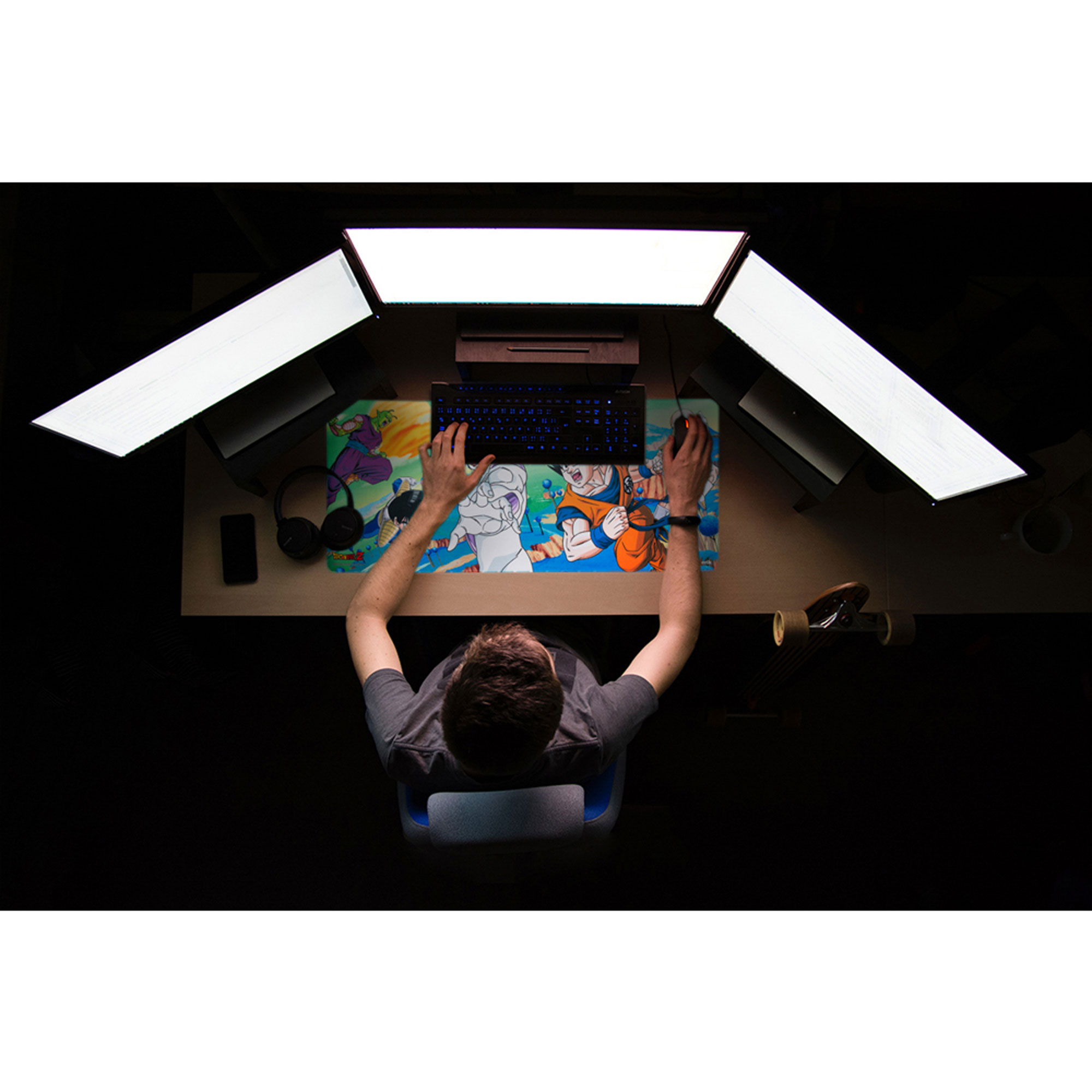 Draufsicht einer Person am Schreibtisch mit Tastatur, Maus und einem Dragon Ball Z Mousepad. Drei Lichter oben.