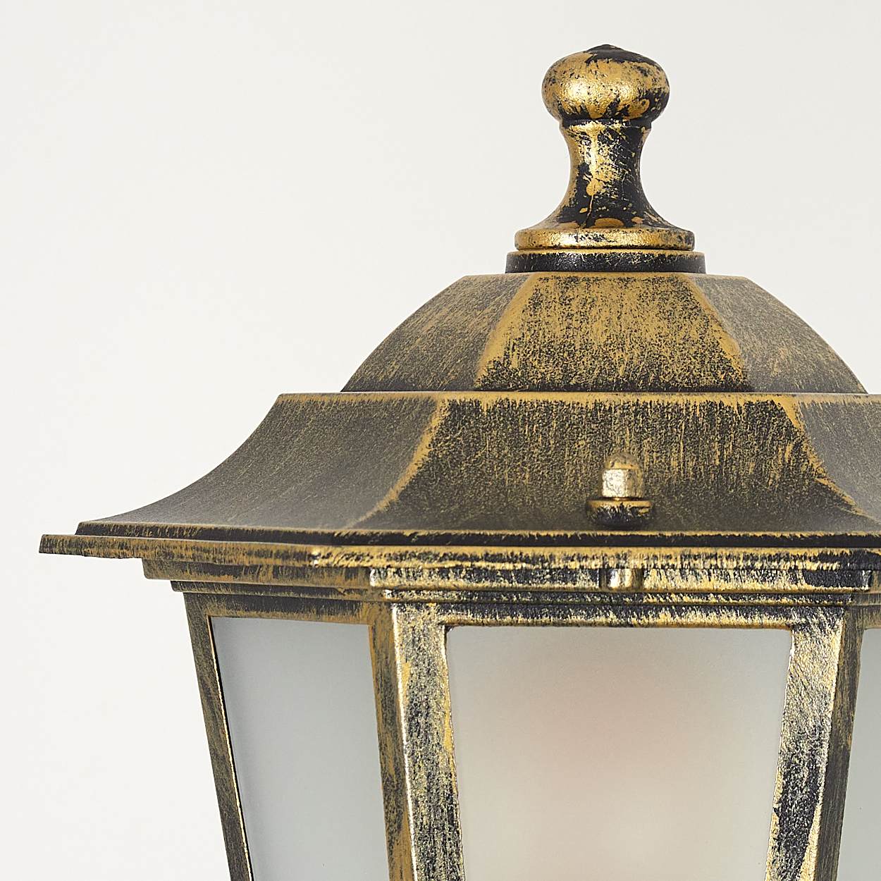 Nahaufnahme einer goldenen Lampe, die Details des oberen Teils und des Milchglases zeigt.
