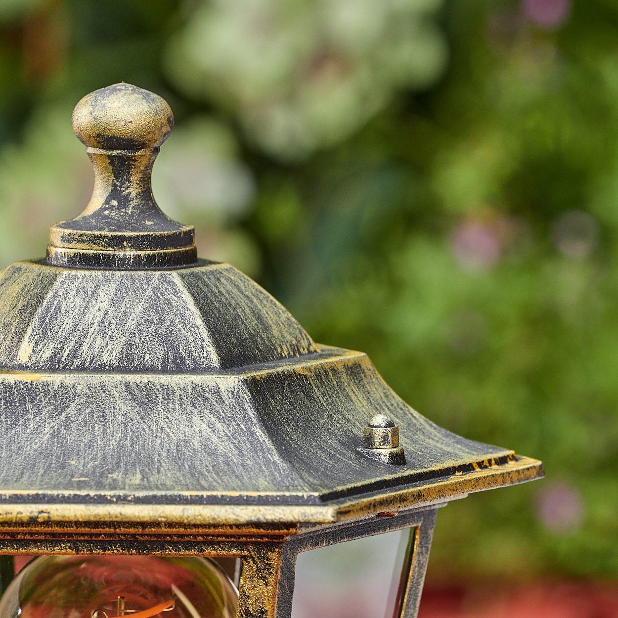 Nahaufnahme einer goldenen und schwarzen Außenlampe. Die Lampe ist verziert, mit verschwommenem Hintergrund.