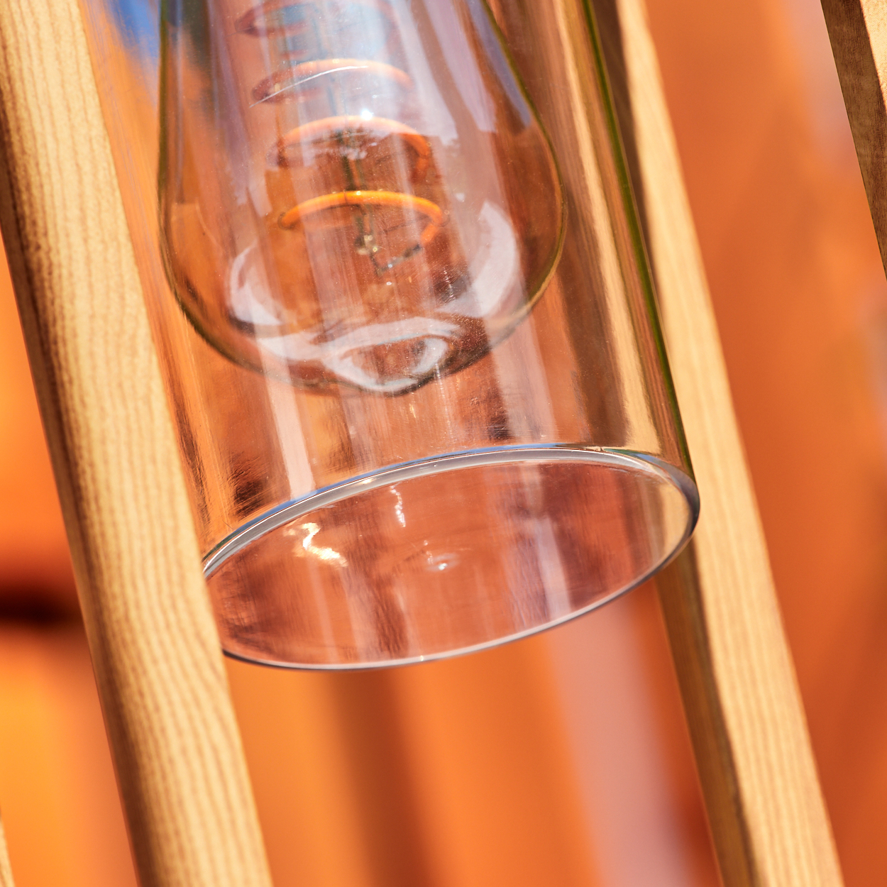 Nahaufnahme einer Glühbirne in einem Glaszylinder, eingerahmt von einer hellen Holzstruktur.