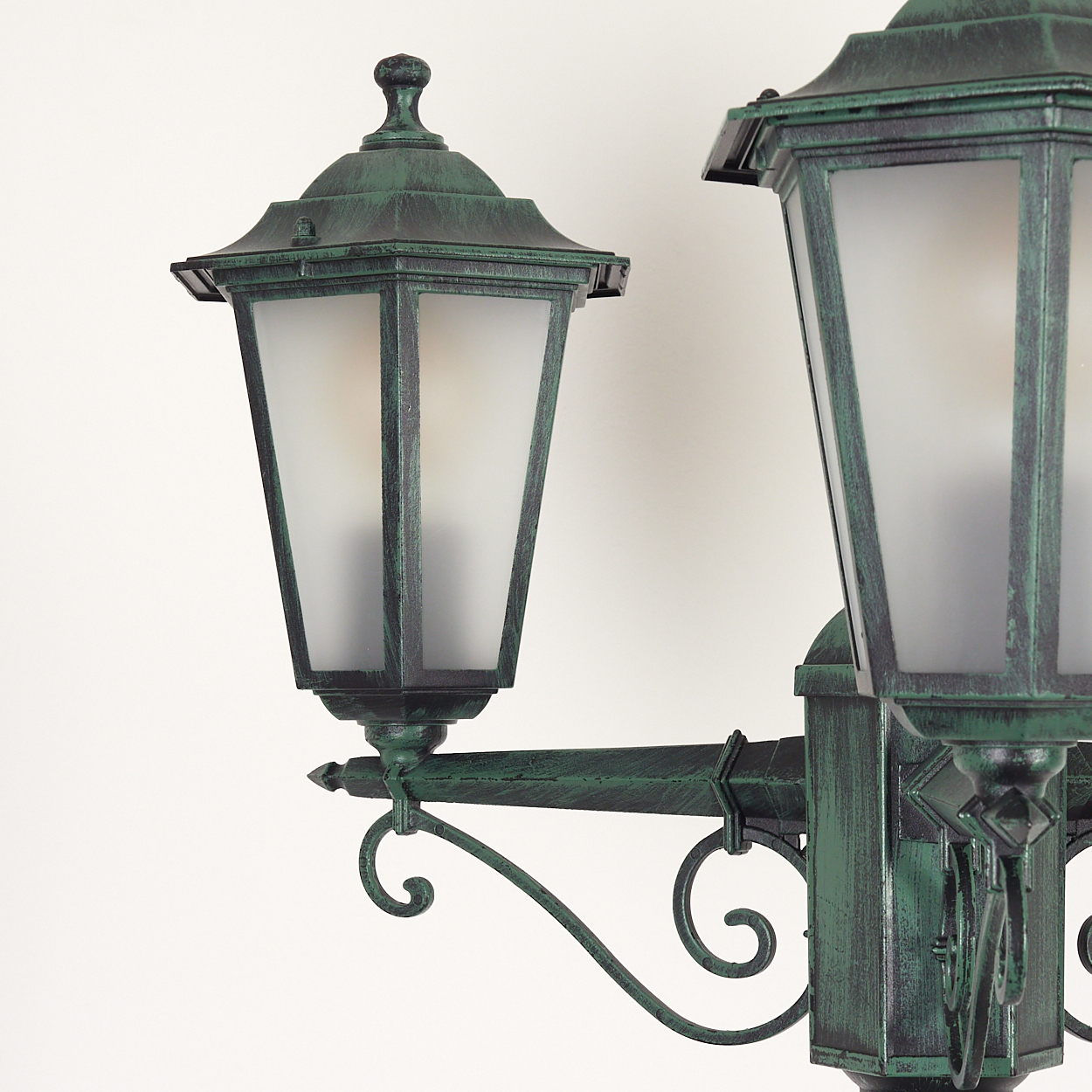 Nahaufnahme einer grünen Außenlampe mit zwei mattierten Glasscheiben vor weißem Hintergrund.