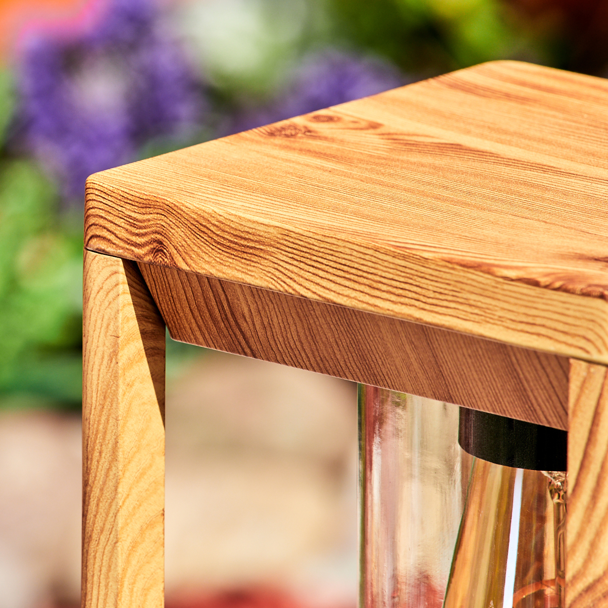 Nahaufnahme eines Holzlampenrahmens mit einem Glasgehäuse, das Holzmaserungsdetails zeigt.
