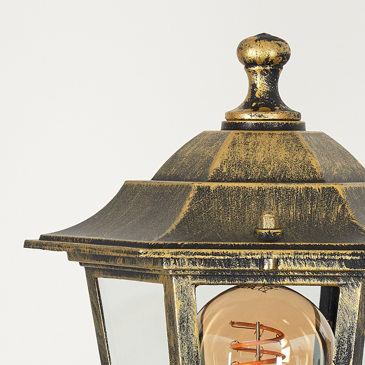 Nahaufnahme einer schwarz-goldenen Lampe. Die Lampe hat eine Glühbirne und ein detailliertes Oberteil.