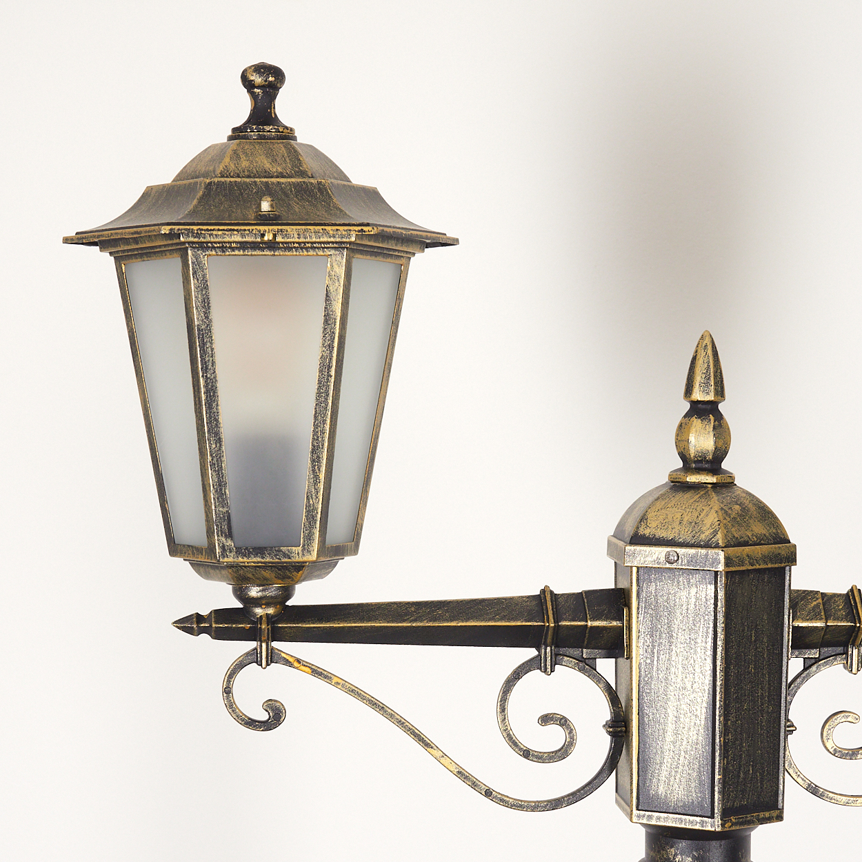 Nahaufnahme einer bronzenen Lampe mit Milchglas. Hat eine dekorative Spitze.