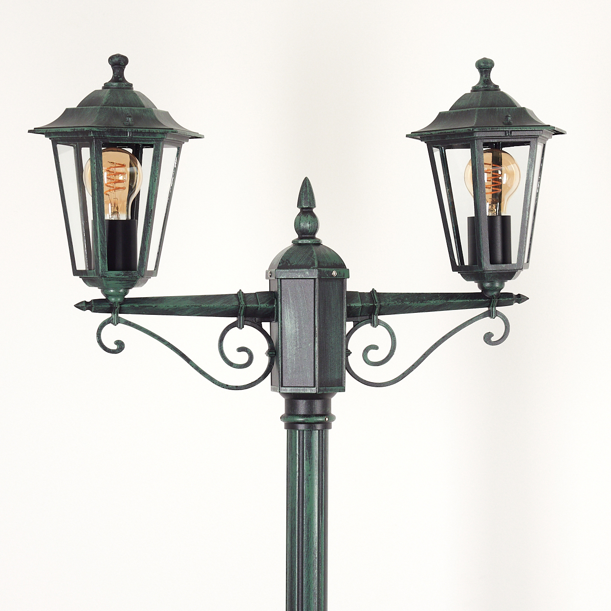 Doppelköpfige Bronze-Lampe mit Glühbirnen, vor weißem Hintergrund. Die Lampen leuchten.