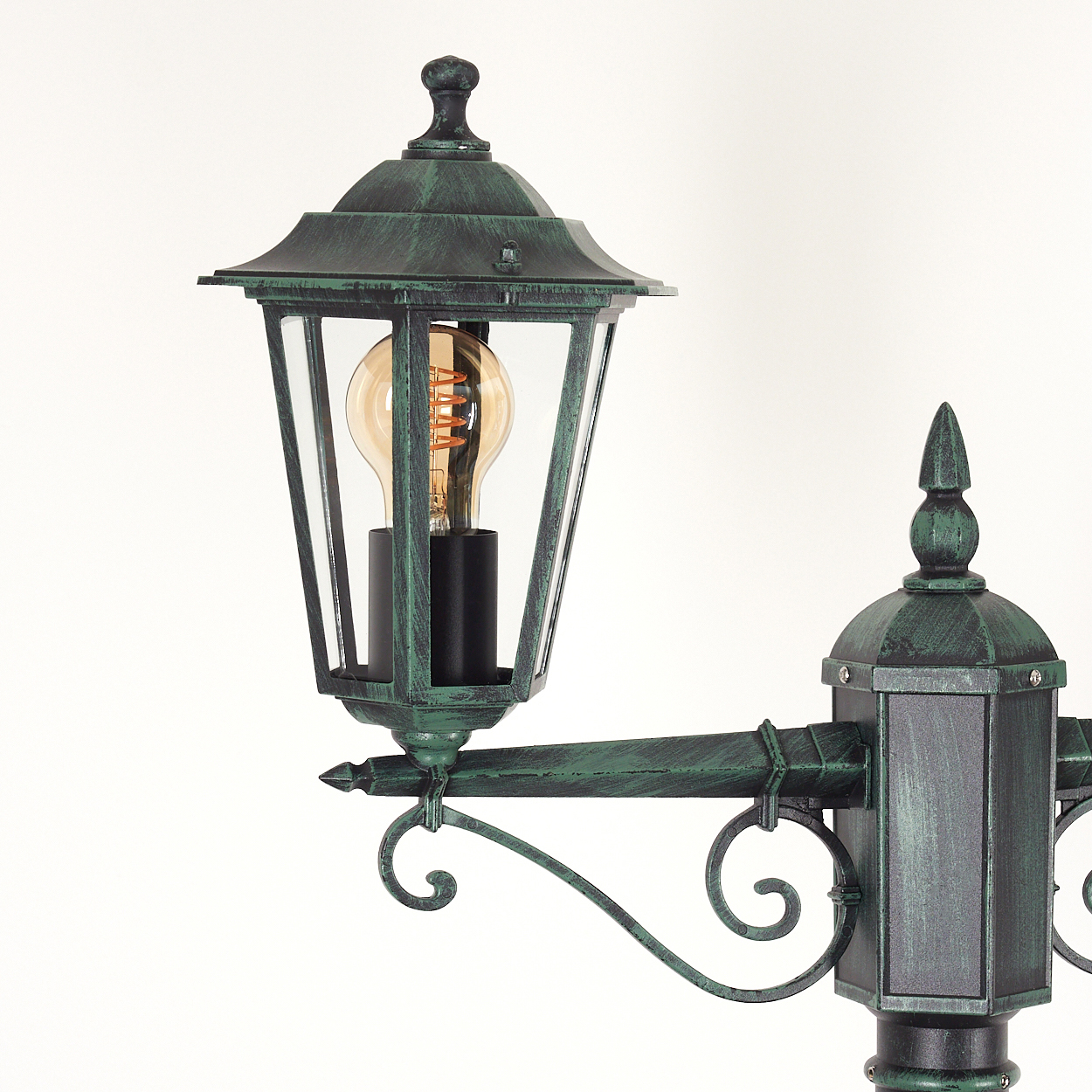 Grüne und schwarze Außenlampe mit Glühbirne, Nahaufnahme auf weißem Hintergrund.