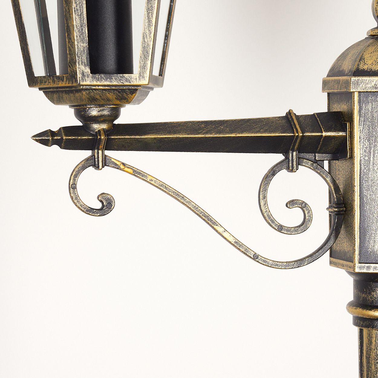 Nahaufnahme eines Außenlampenarms mit dekorativem Scroll-Design, goldene Farbe.