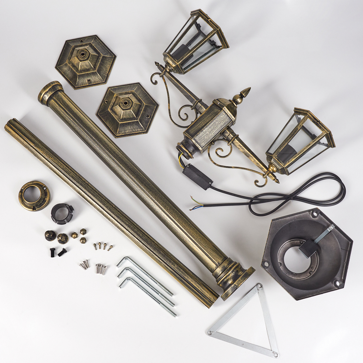Goldene Lampenpfahlteile ausgelegt. Teile liegen auf weißer Fläche.