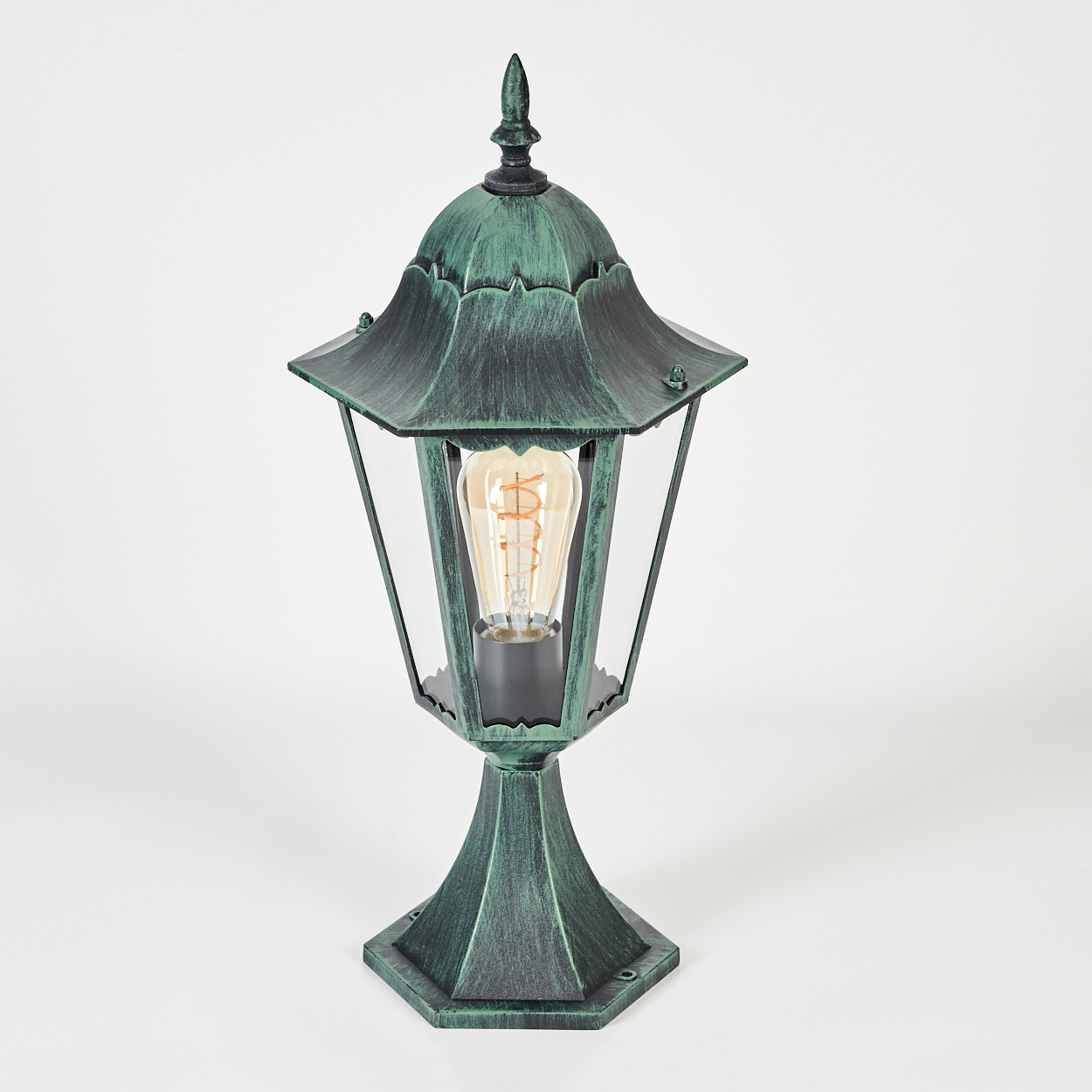 Grüne Außenlampe auf weißem Hintergrund. Die Lampe hat eine Glühbirne im Inneren.