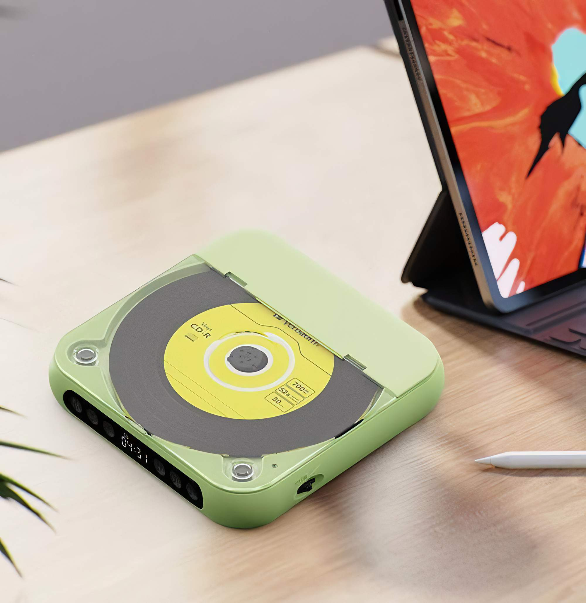 Grüner tragbarer CD-Player mit eingelegter CD. Auf einem Holztisch mit Tablet.