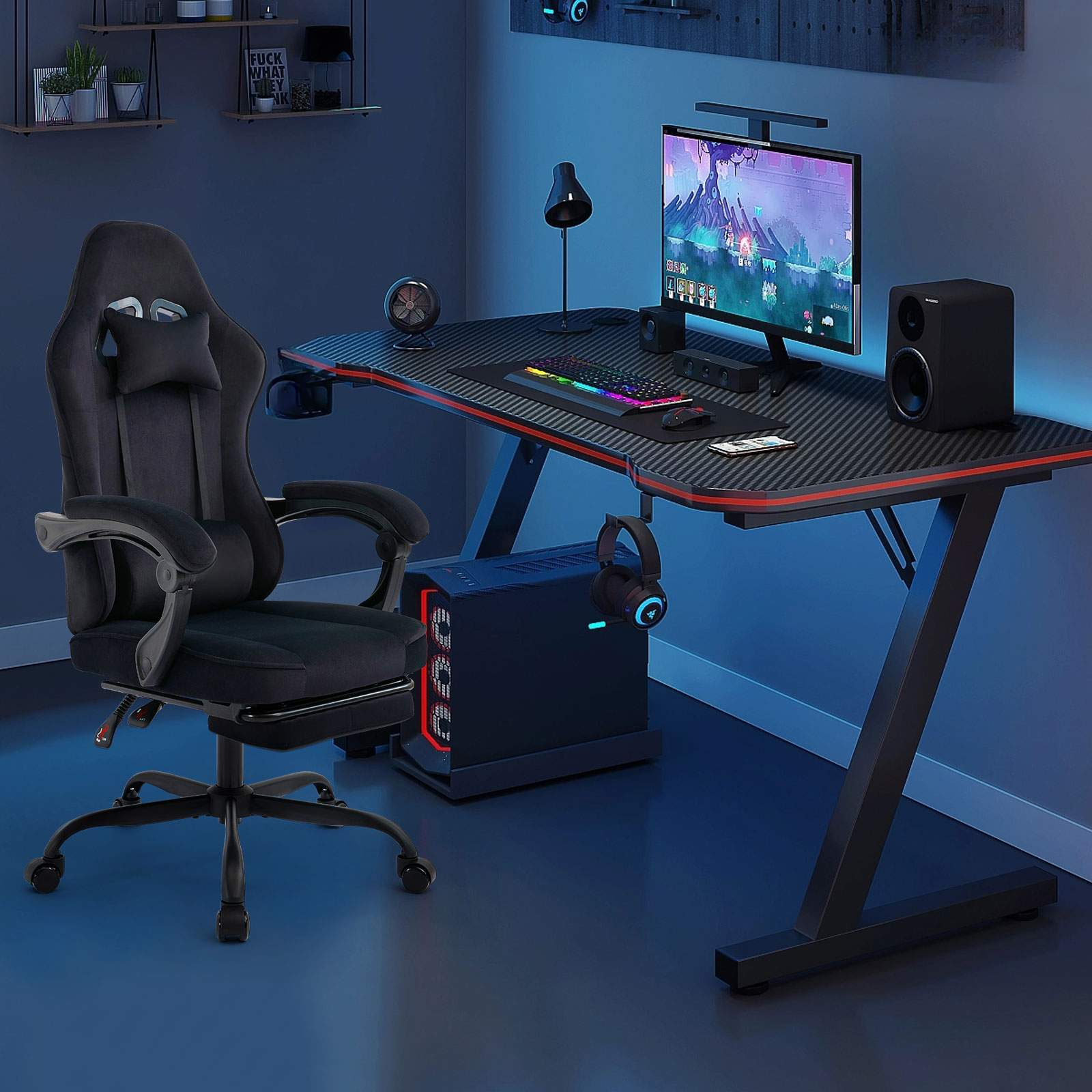 Schwarzes Gaming-Setup mit schwarzem Stuhl. Schreibtisch, Monitor und Lautsprecher im Bild.
