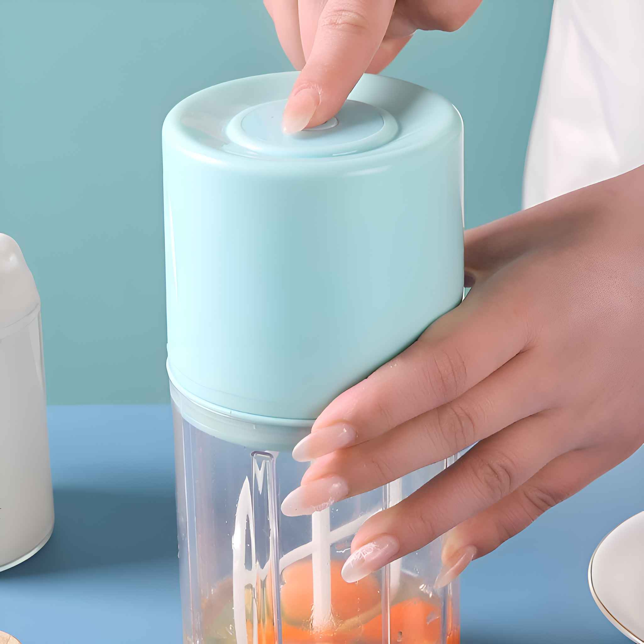 Hände benutzen einen blauen Food-Processor, um Essen zu hacken, mit transparentem Behälter.