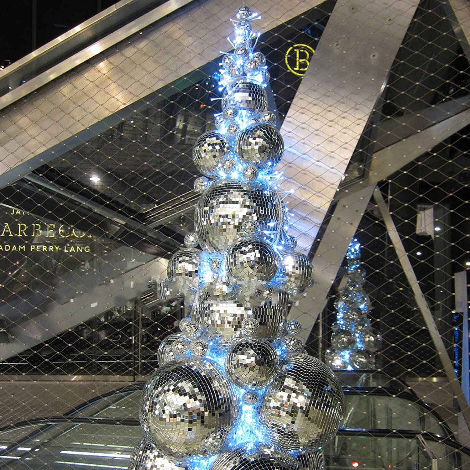 Ein Weihnachtsbaum aus silbernen Discokugeln mit Lichtern. Hintergrund ist ein Gebäudeinneres.
