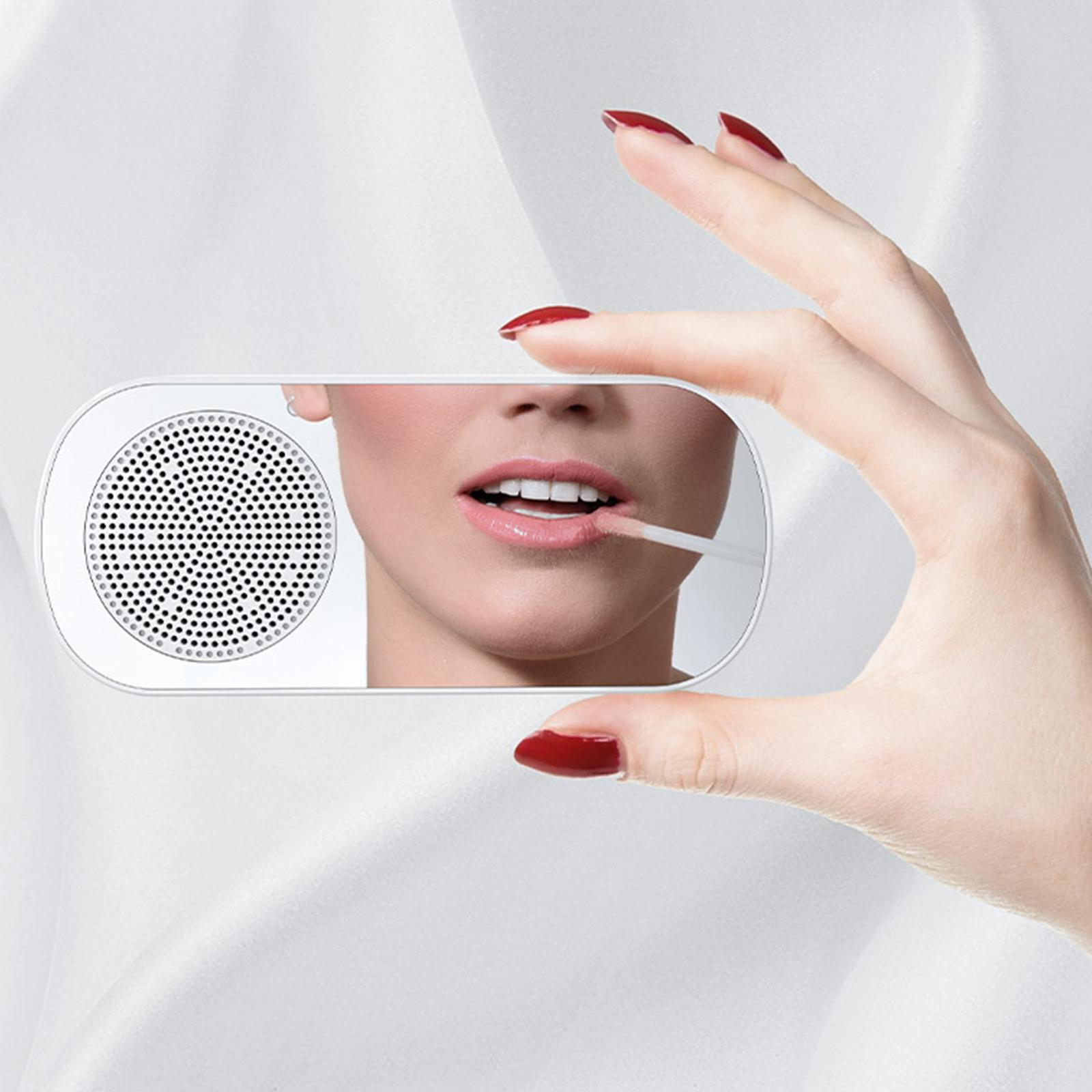 Eine Hand hält einen kleinen Spiegel, der ihr Gesicht reflektiert. Sie trägt Lipgloss auf, der Hintergrund ist weißer Stoff.