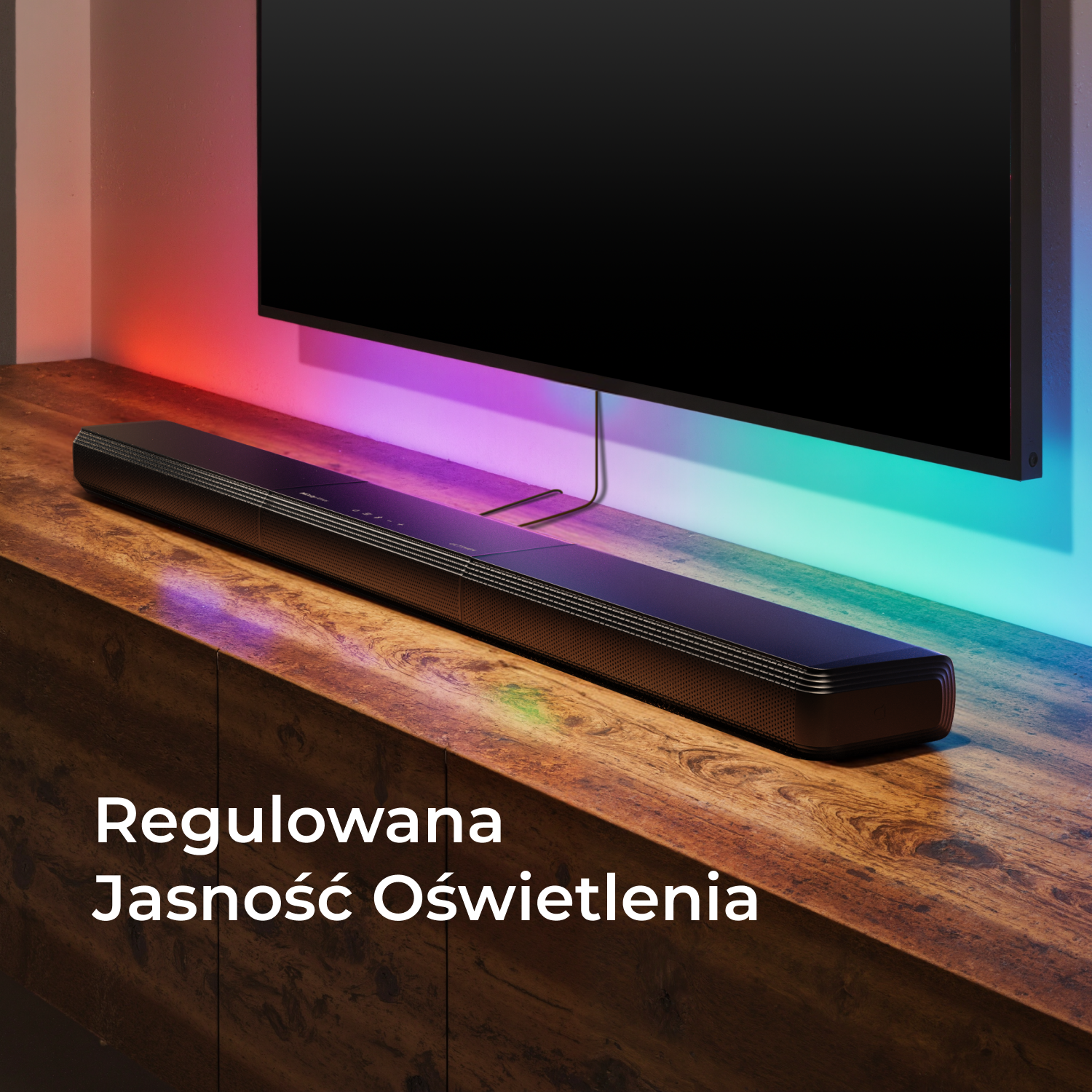 Soundbar na drewnianej szafce pod telewizorem, z regulowanym światłem.
