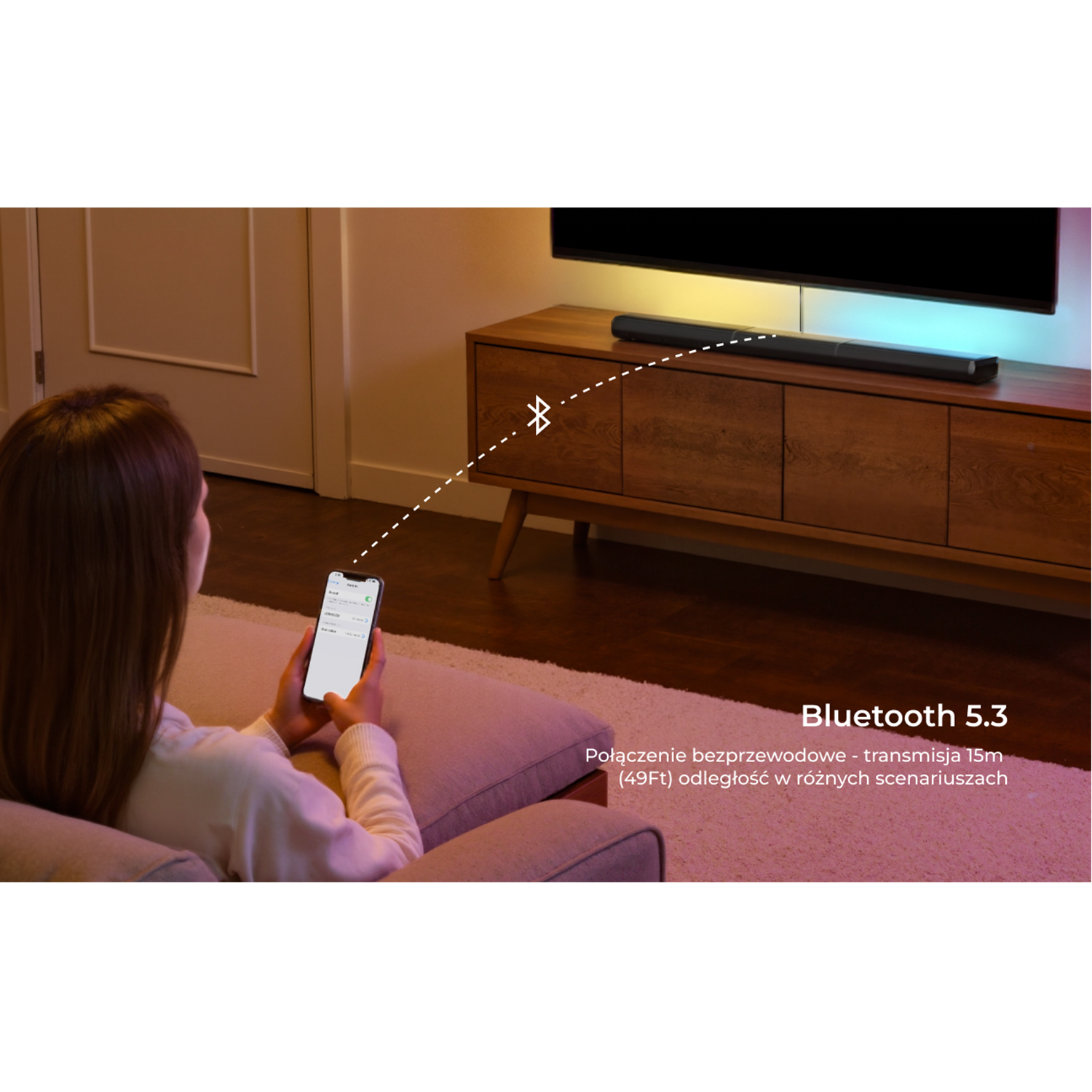 Kobieta używa telefonu, połączonego z soundbarem przez Bluetooth. TV i szafka w tle.