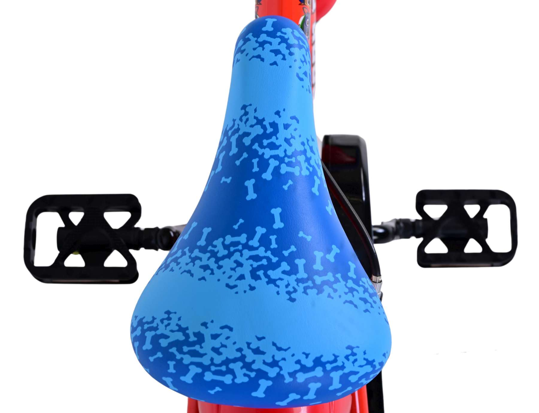 Nahaufnahme eines Fahrradsitzes. Blau mit knochenförmigen Mustern, roter Fahrradrahmen und schwarze Pedale.