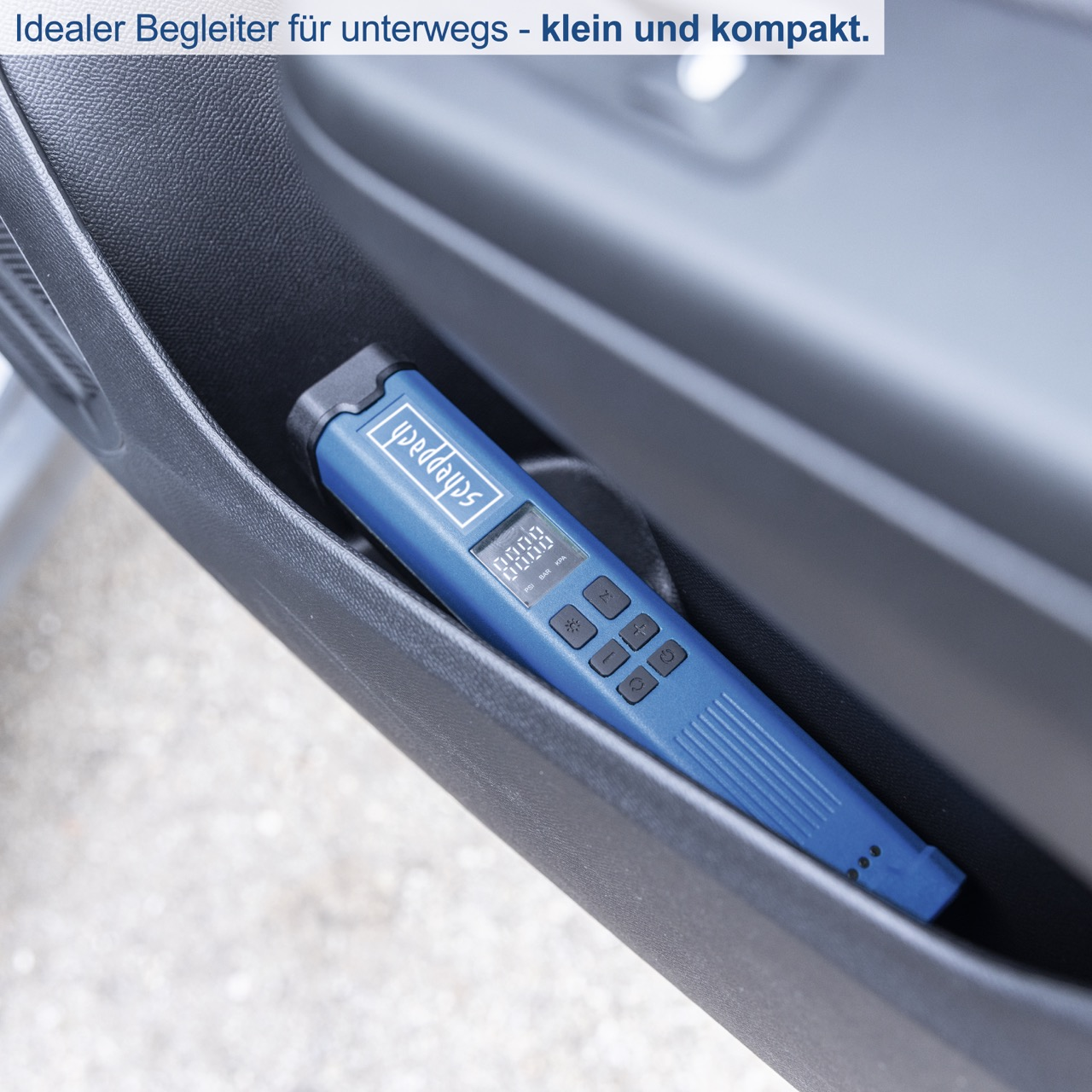 Ein kleines blaues Gerät in einer Autotür-Tasche. Das Gerät hat ein Display und Knöpfe, mit Text.
