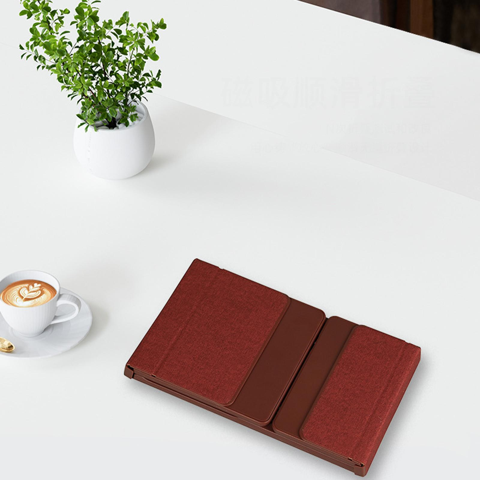 Tastatur, Kaffee und eine kleine Pflanze auf einem weißen Tisch. Die Tastatur ist gefaltet.