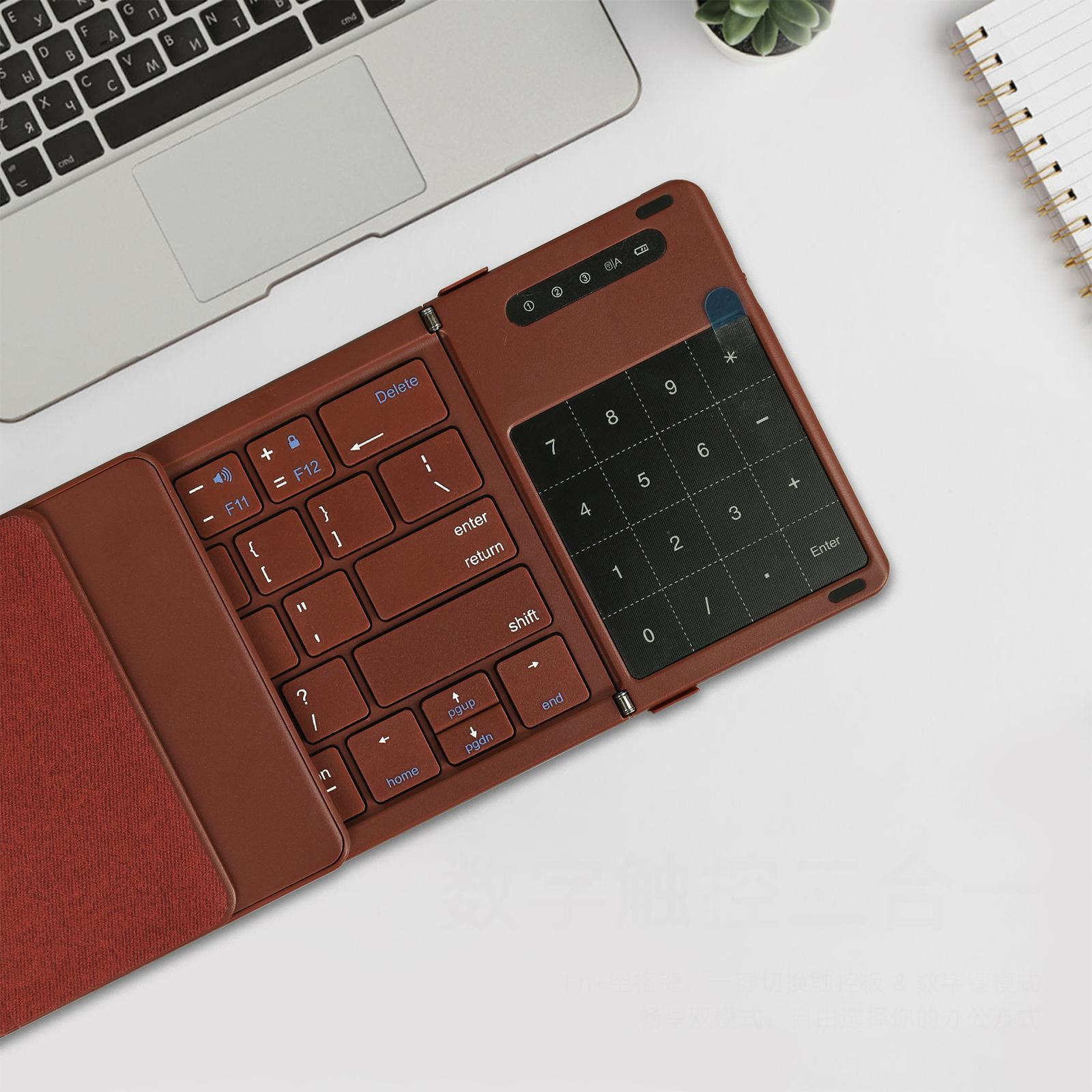 Eine braune, faltbare Tastatur mit Nummernblock auf weißer Oberfläche. Ein Laptop im Hintergrund.