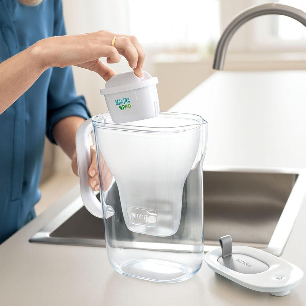 Una persona sta mettendo un filtro per l'acqua bianco in una caraffa per l'acqua, accanto al coperchio della caraffa.