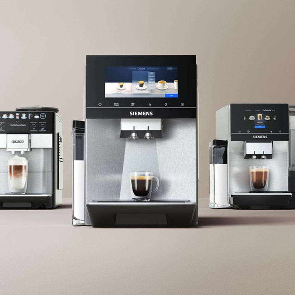 Trzy ekspresy do kawy z ekranem cyfrowym wyświetlającym opcje kawy. Filiżanka pod środkowym ekspresem.
