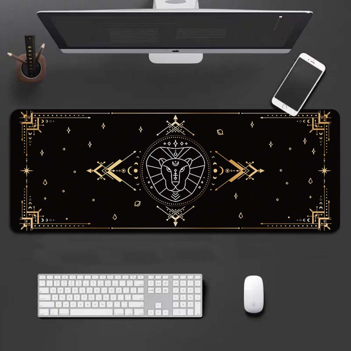 Black desk mat with a zodiac design, a keyboard, a mouse, a monitor, and a phone.