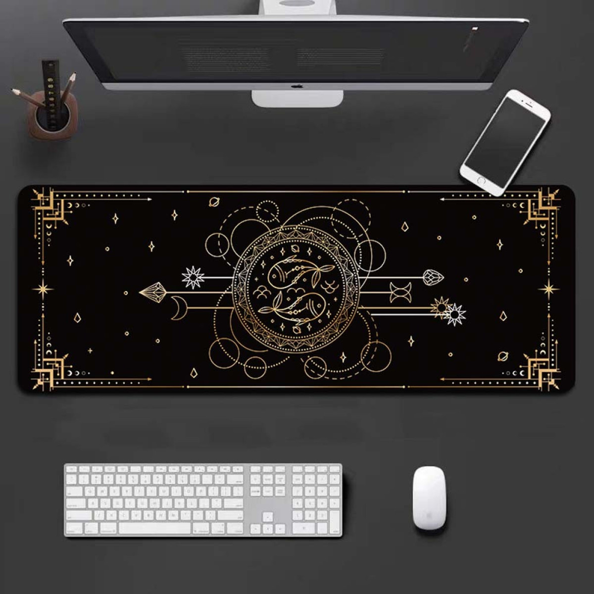 Black desk mat with golden celestial design featuring Pisces symbols. Keyboard, mouse, phone, monitor.