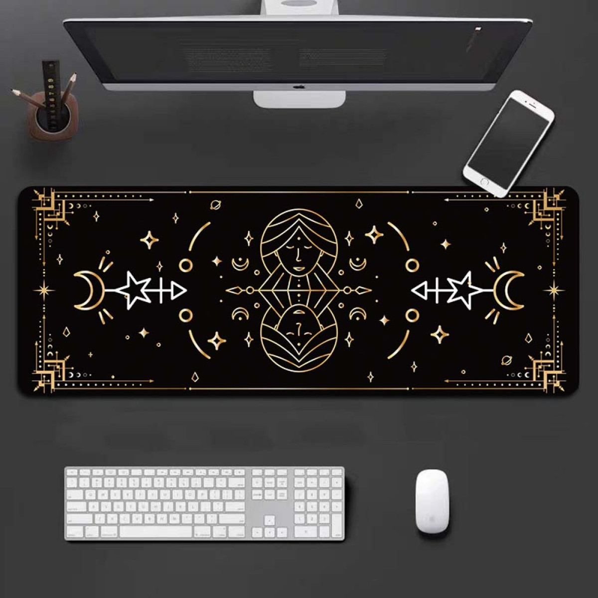A black desk mat with a celestial design. A computer, keyboard, mouse, and phone are on it.