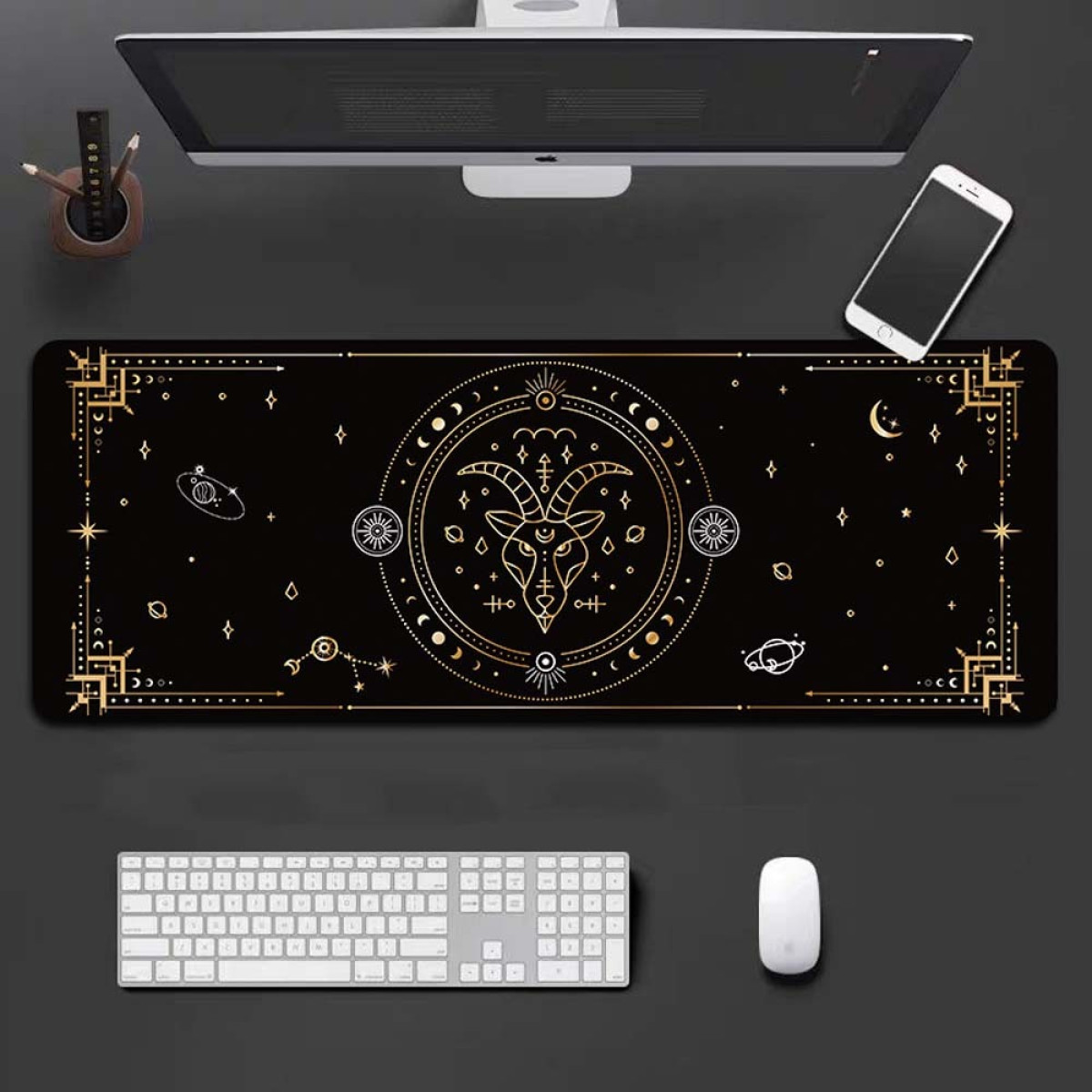 A black desk mat with a golden design, a keyboard, mouse, phone, and a computer monitor.
