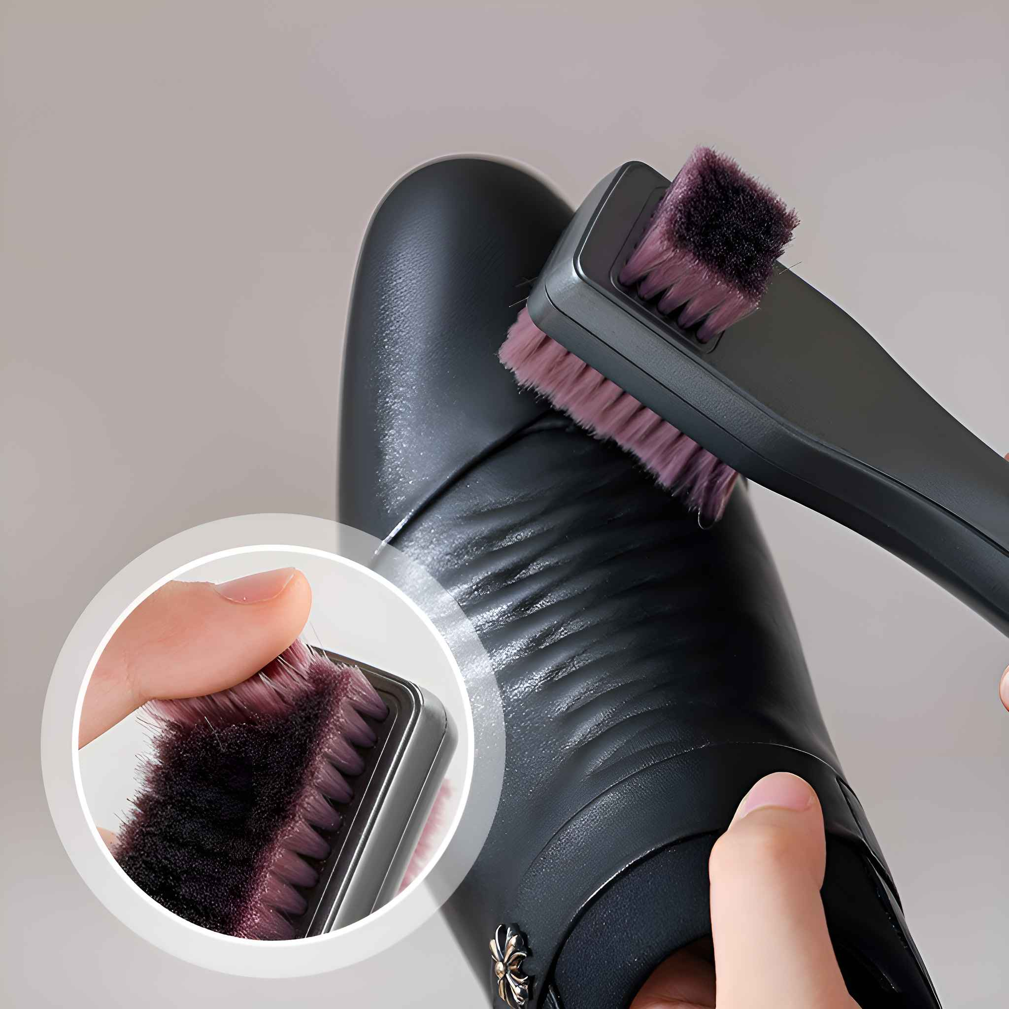 Eine Hand reinigt einen schwarzen Schuh mit einer schwarzen Bürste. Die Bürste hat lila Borsten.