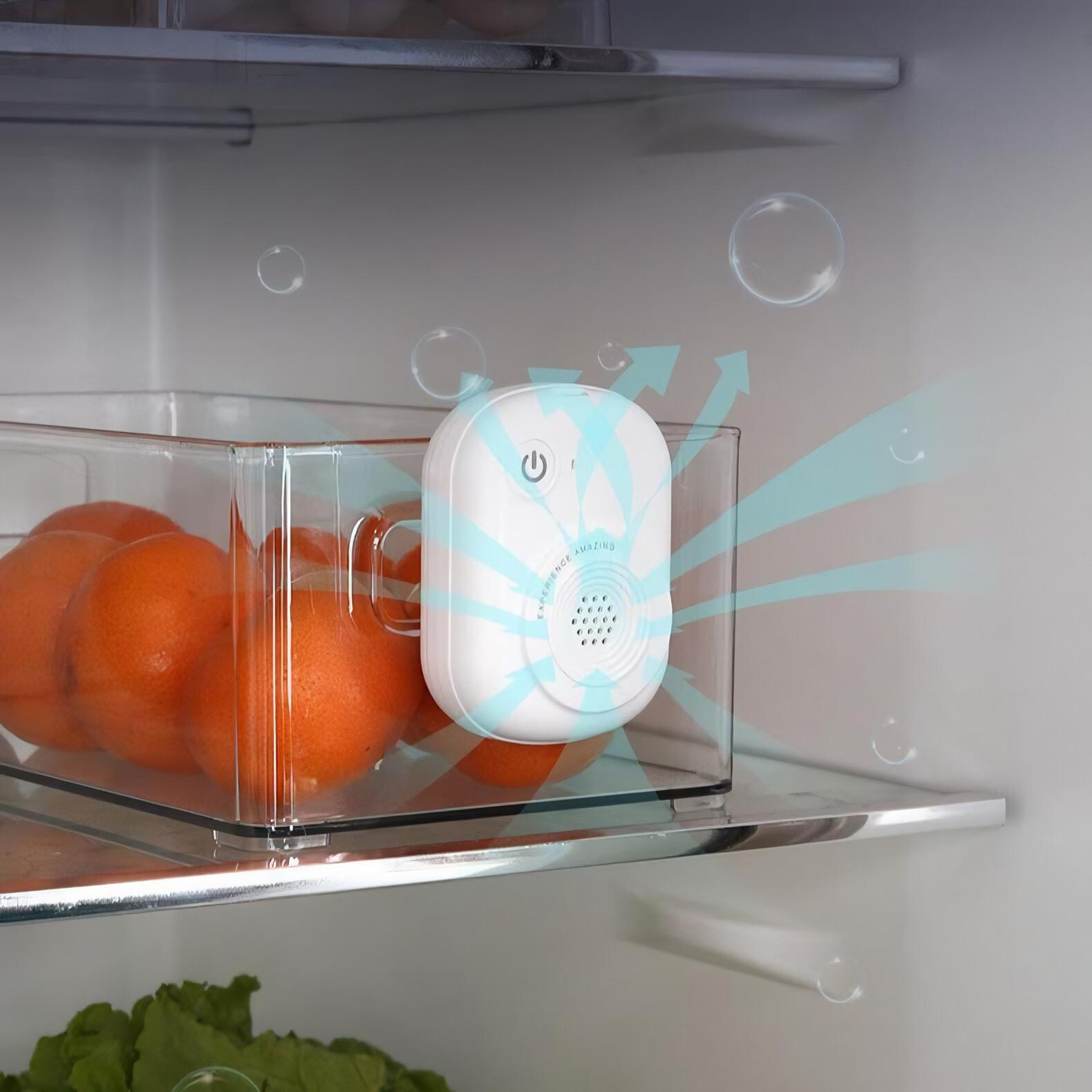 Ein weißes Gerät in einem Kühlschrank emittiert Luft. Orangen befinden sich in einem durchsichtigen Behälter. Blasen schweben. Der Hintergrund ist der Kühlschrank.