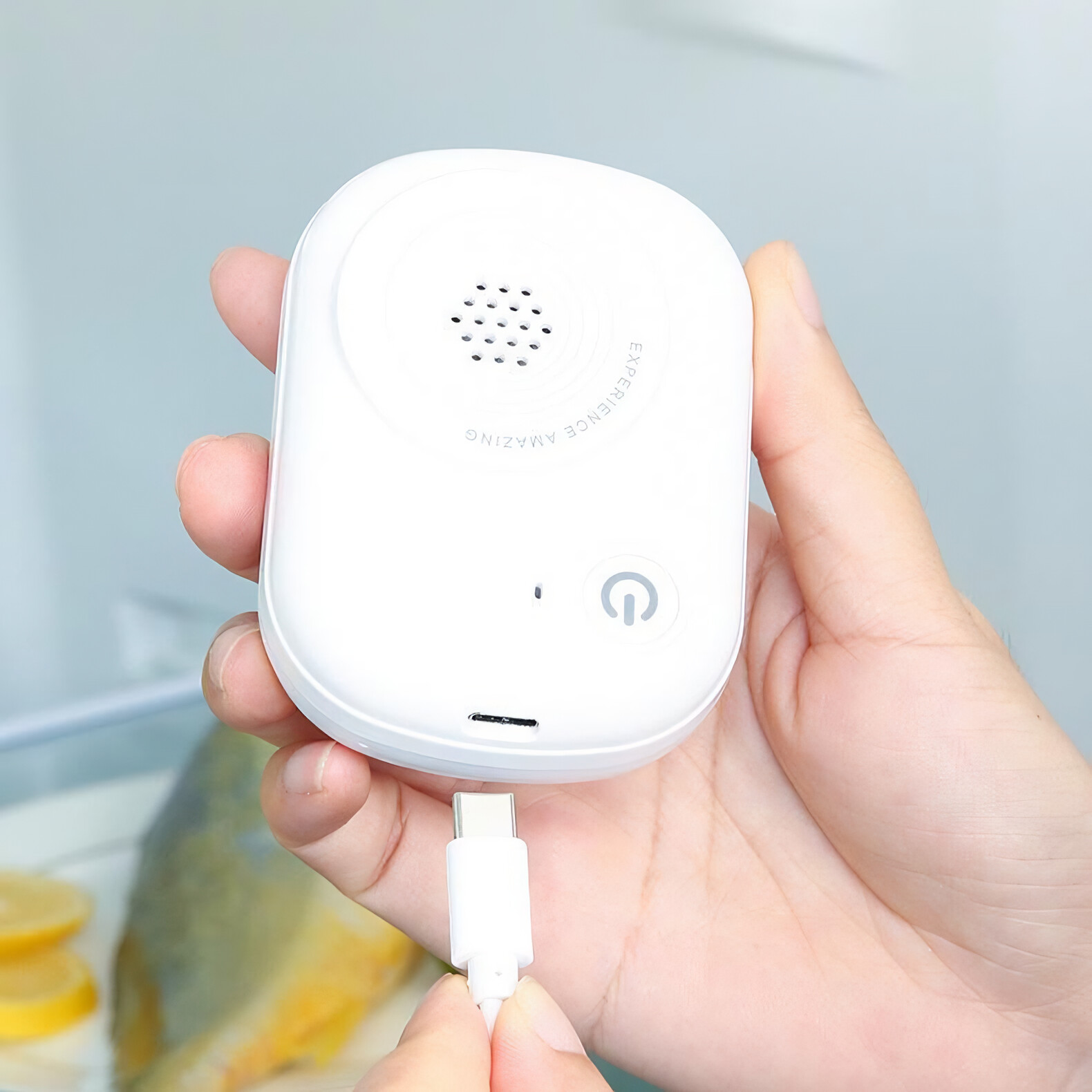 Hand hält ein weißes Gerät mit einem USB-C-Kabel. Der Text 'Experience Amazing' ist sichtbar.
