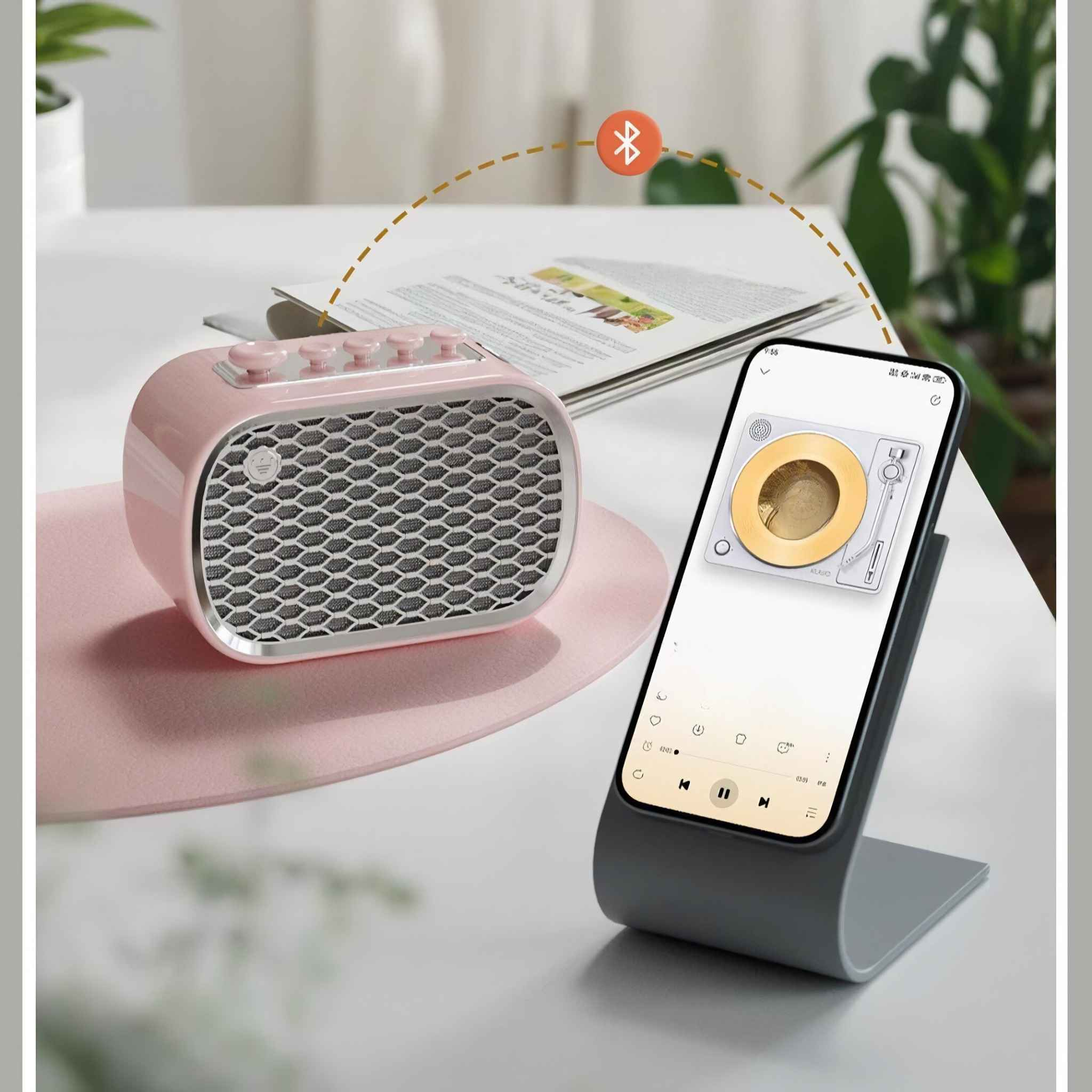 Ein rosa Lautsprecher neben einem Telefon auf einem Ständer, auf dem Telefon wird eine Plattenspieler-Oberfläche angezeigt.