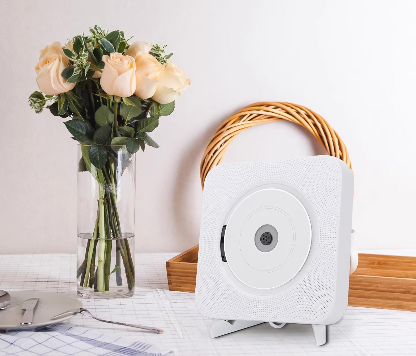 Ein weißer CD-Player mit einer weißen Disc in der Mitte und einem Rosenstrauß in der Nähe.