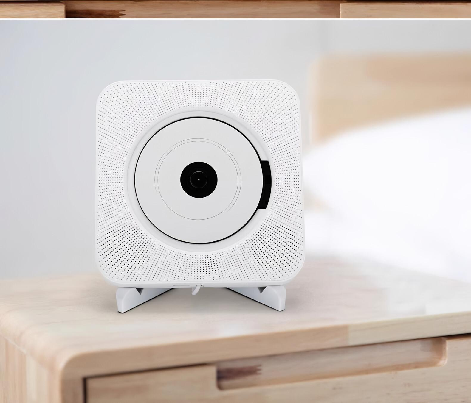 Weißer CD-Player auf einem Holztisch. Er hat einen kreisförmigen Disc-Schlitz und einen Ständer.