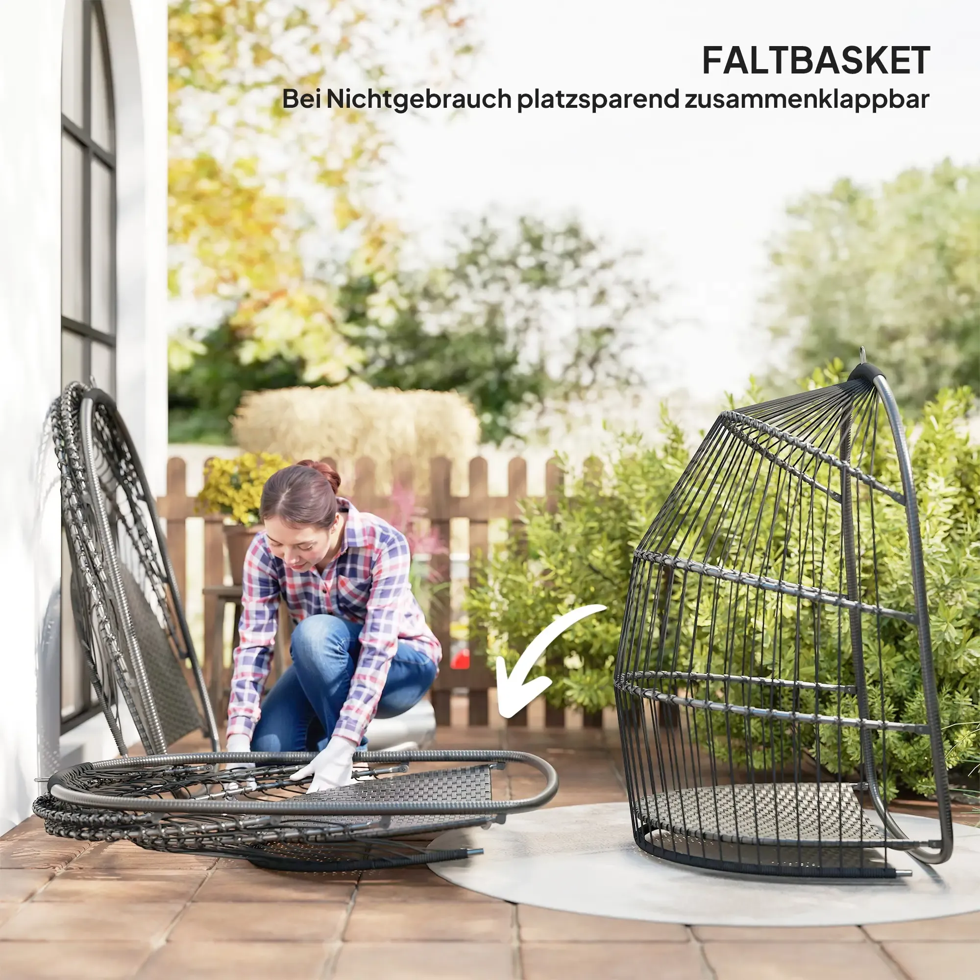 Eine Frau montiert einen Hängestuhl. Der Stuhl ist aus schwarzem Korbgeflecht. Ein zweiter Stuhl ist zusammengeklappt in der Nähe. Draußen auf einer Terrasse.