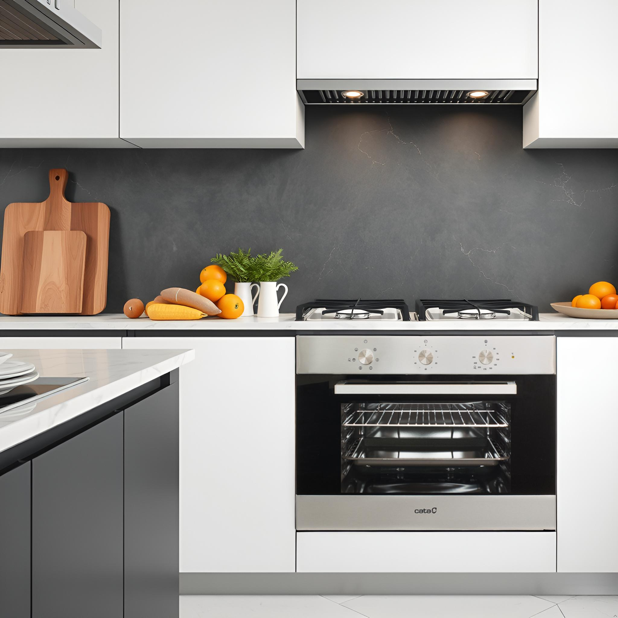 Cucina con mobili bianchi, paraschizzi scuro e forno. Frutta e utensili sul bancone.