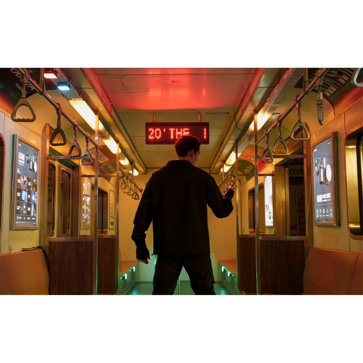 Person steht in einer U-Bahn, schaut zum Ende. Der Wagen hat Lichter und Anzeigen an den Seitenwänden.