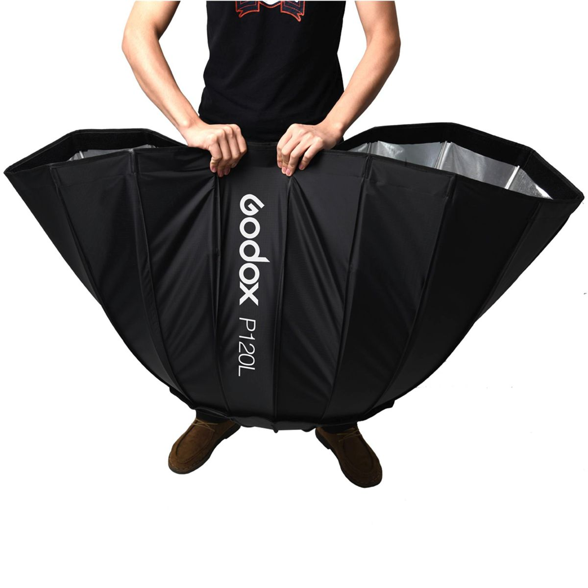 Eine Person hält eine große, schwarz-weiße Softbox mit dem Godox P120L Logo.