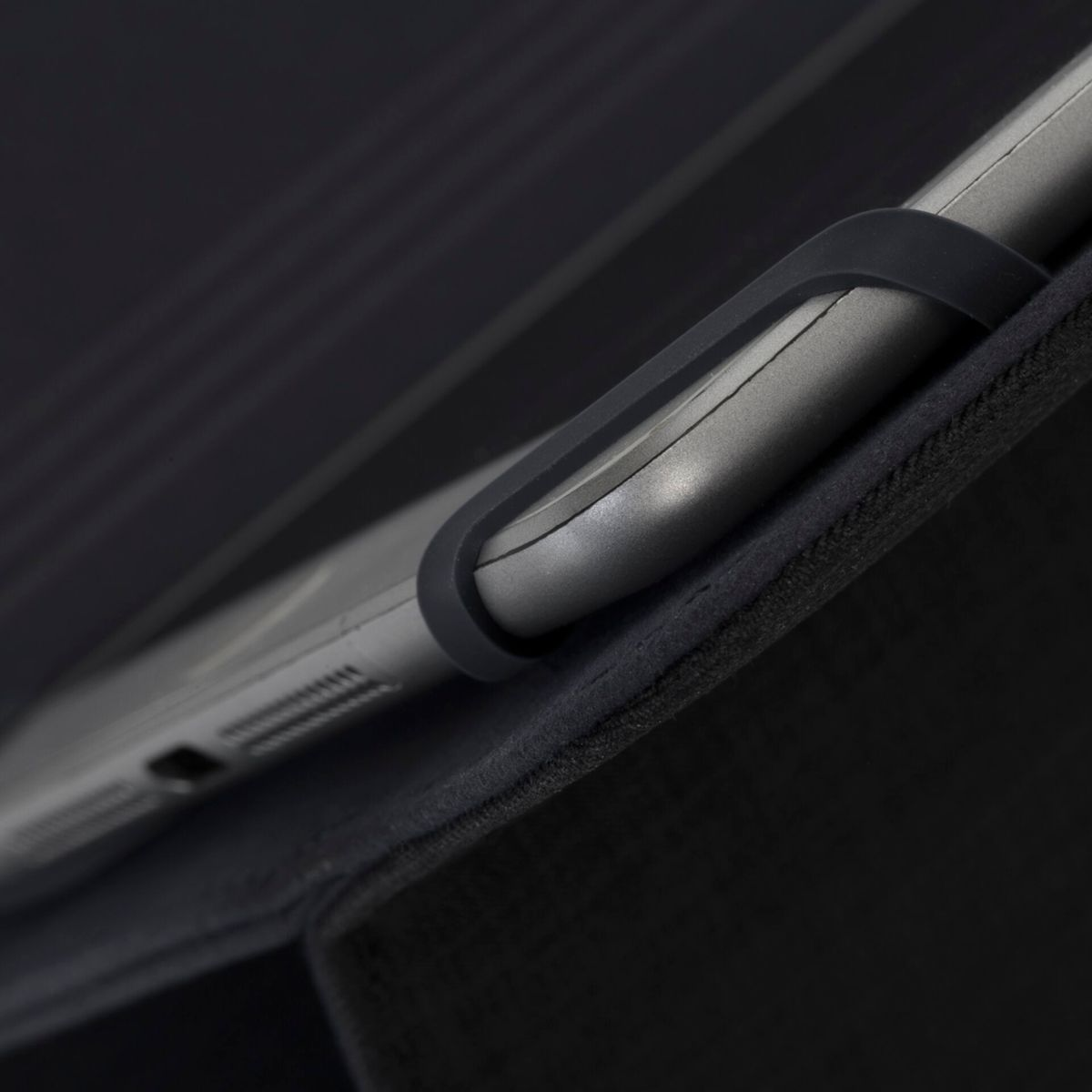 Zbliżenie rogu tabletu w czarnym etui, pokazujące urządzenie i krawędź etui.