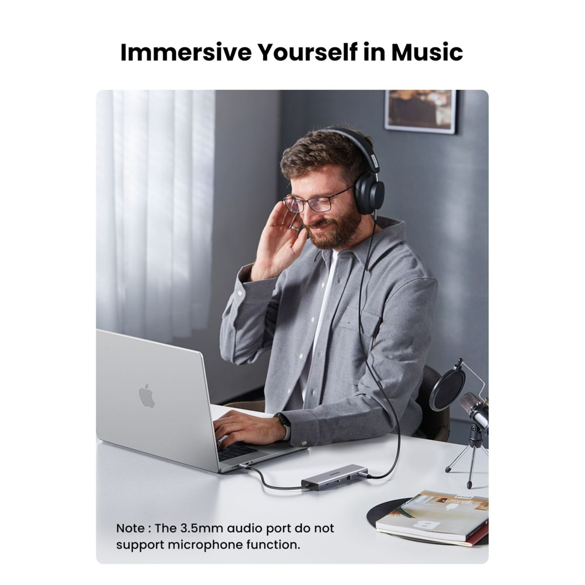 Mężczyzna w słuchawkach i okularach słucha muzyki na laptopie.